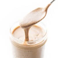 spoon pouring mixed nut butter into a mason jar