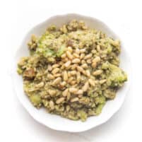 pesto cauliflower rice, broccoli, meatballs and pinenuts in a white bowl