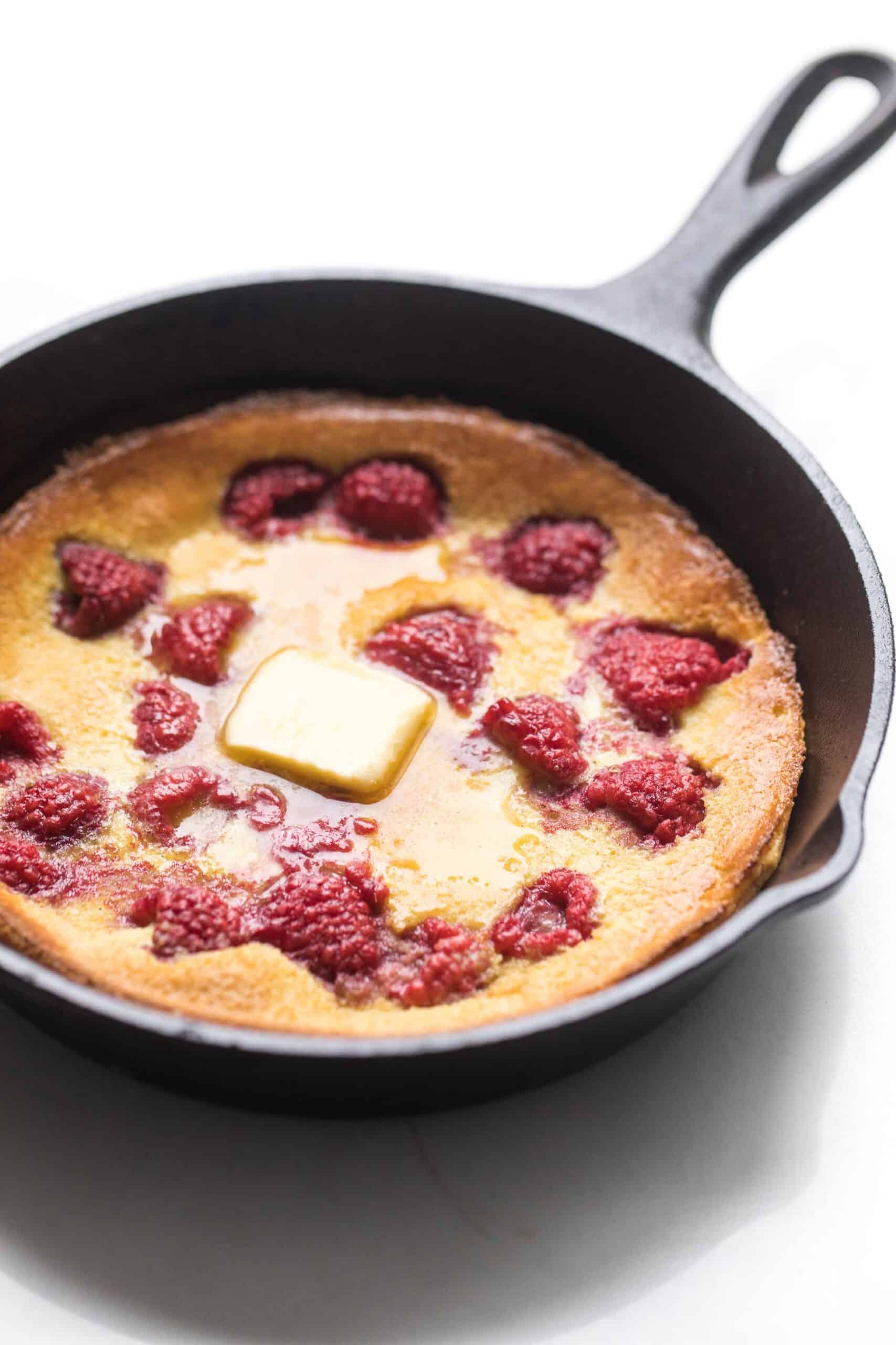 keto dutch baby pancake in a cast iron skillet with raspberries