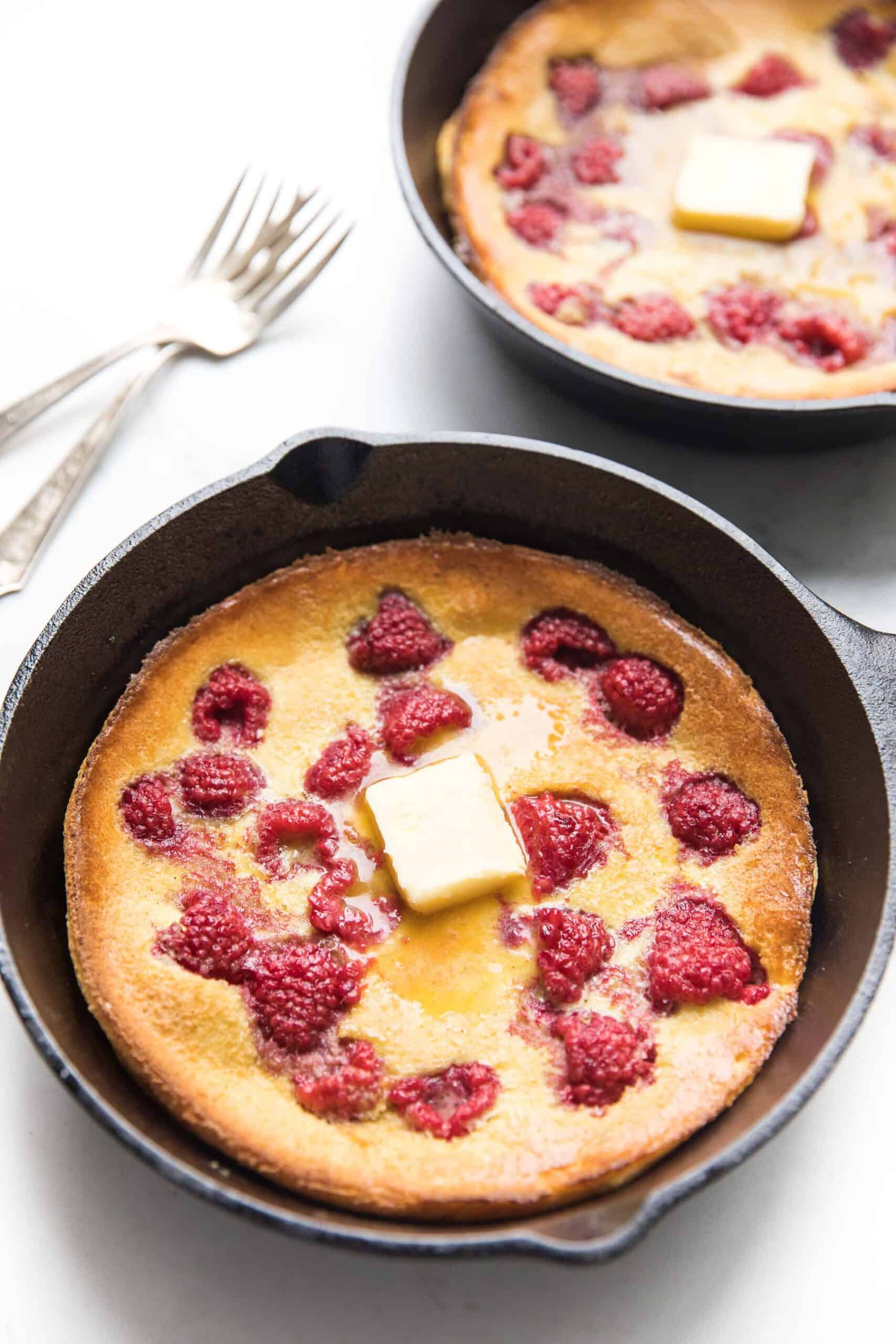 keto dutch baby pancake in a cast iron skillet with raspberries