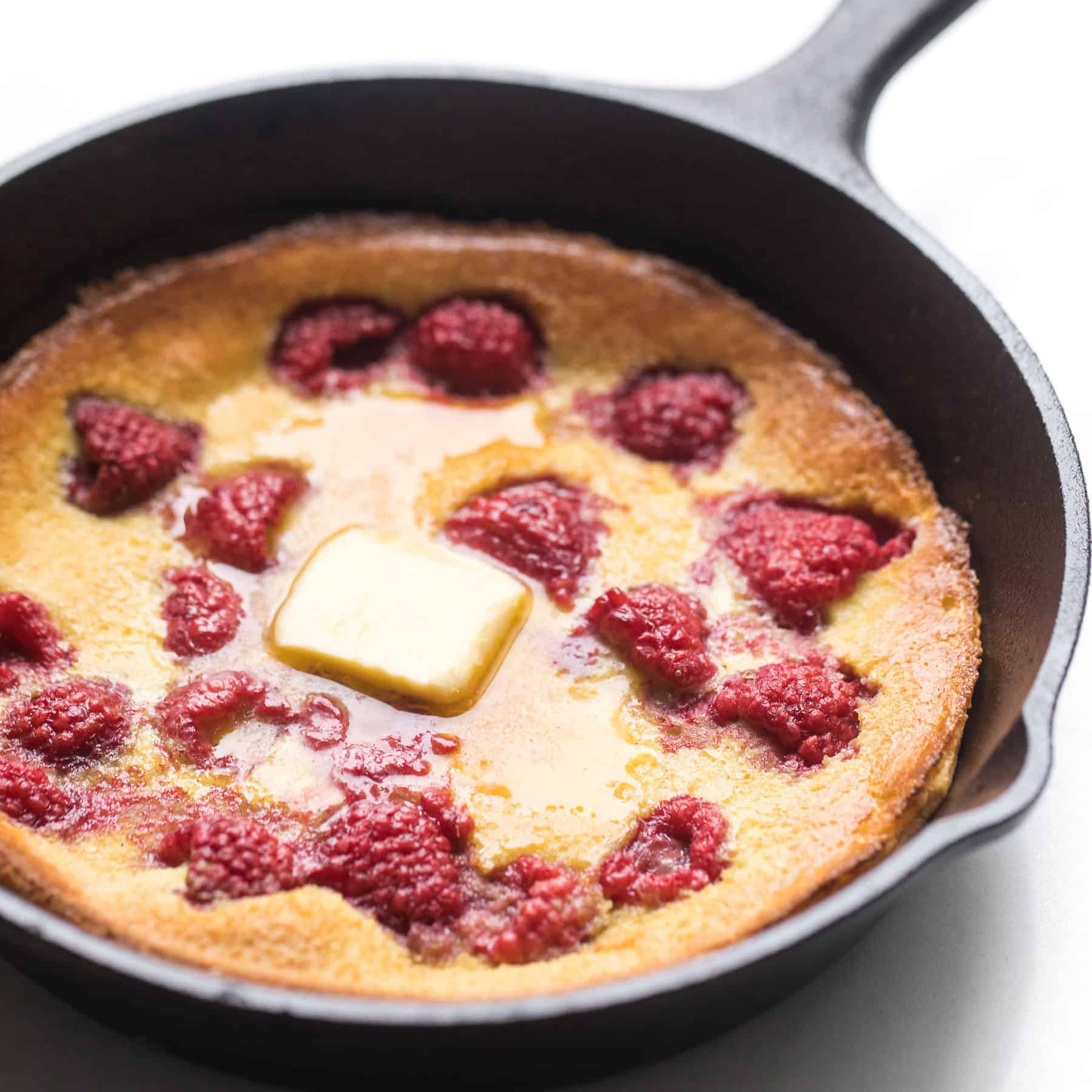 keto dutch baby pancake in a cast iron skillet with raspberries