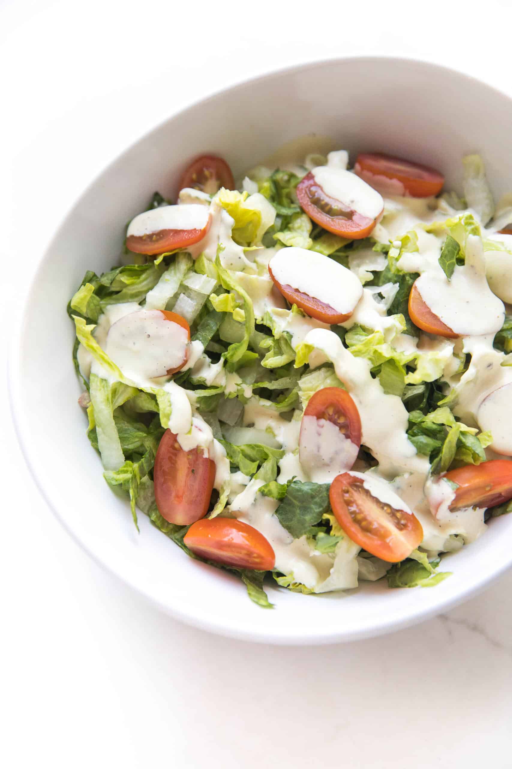 pouring caesar dressing over salad