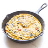 frittata in a cast iron skillet and white background