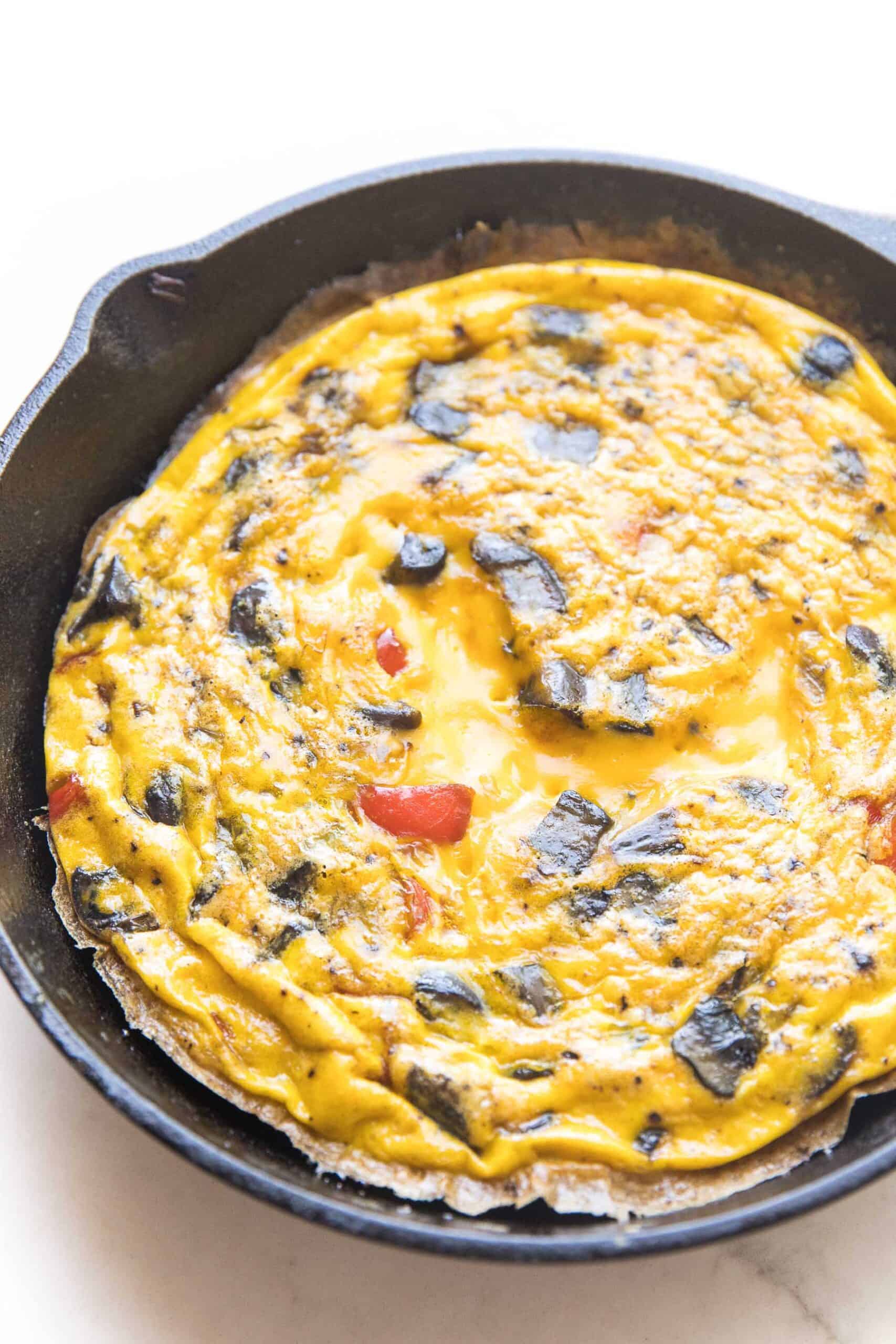 frittata in a cast iron skillet and white background