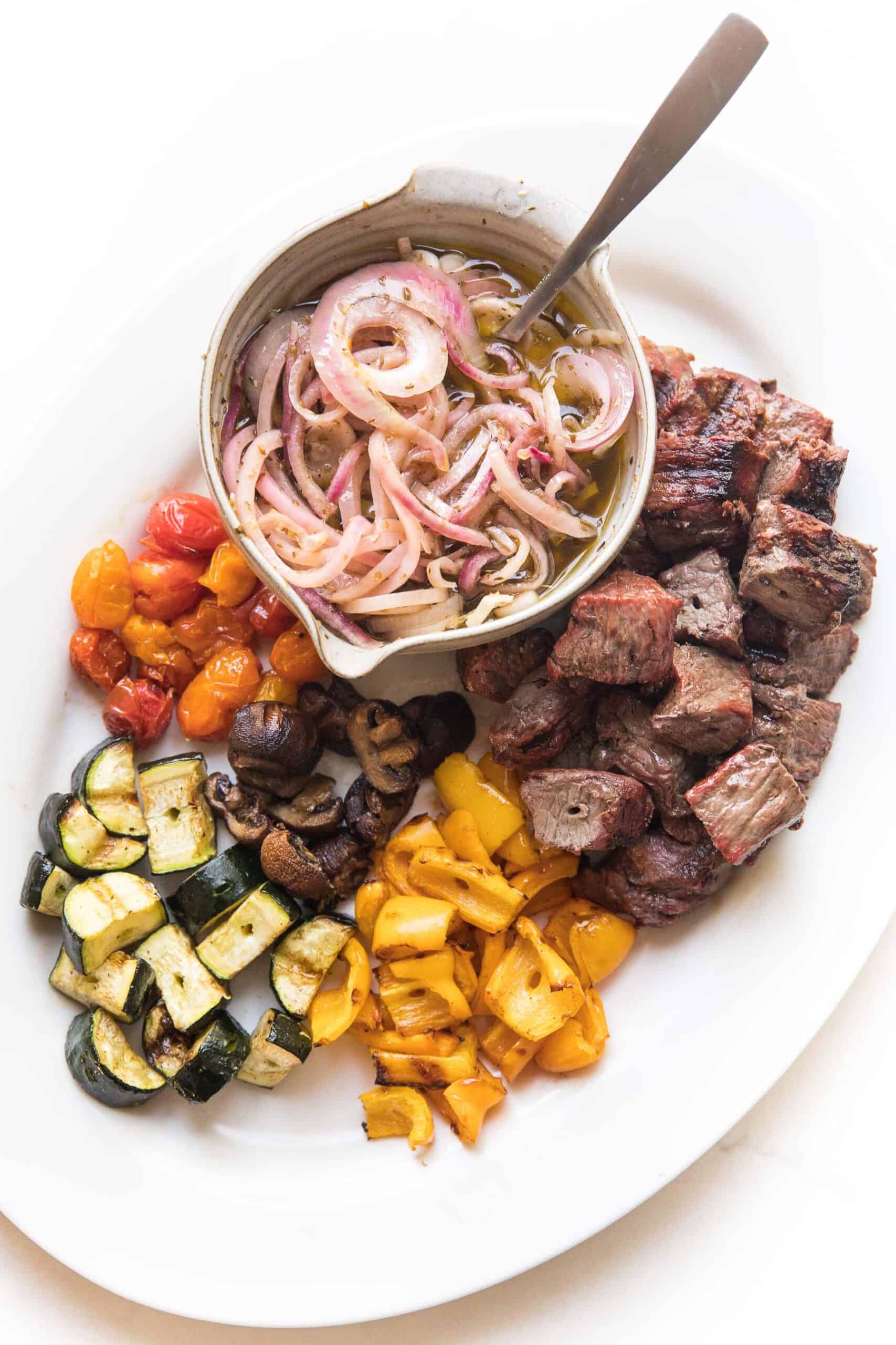 grilled steak and vegetable kabob skewers on a white platter