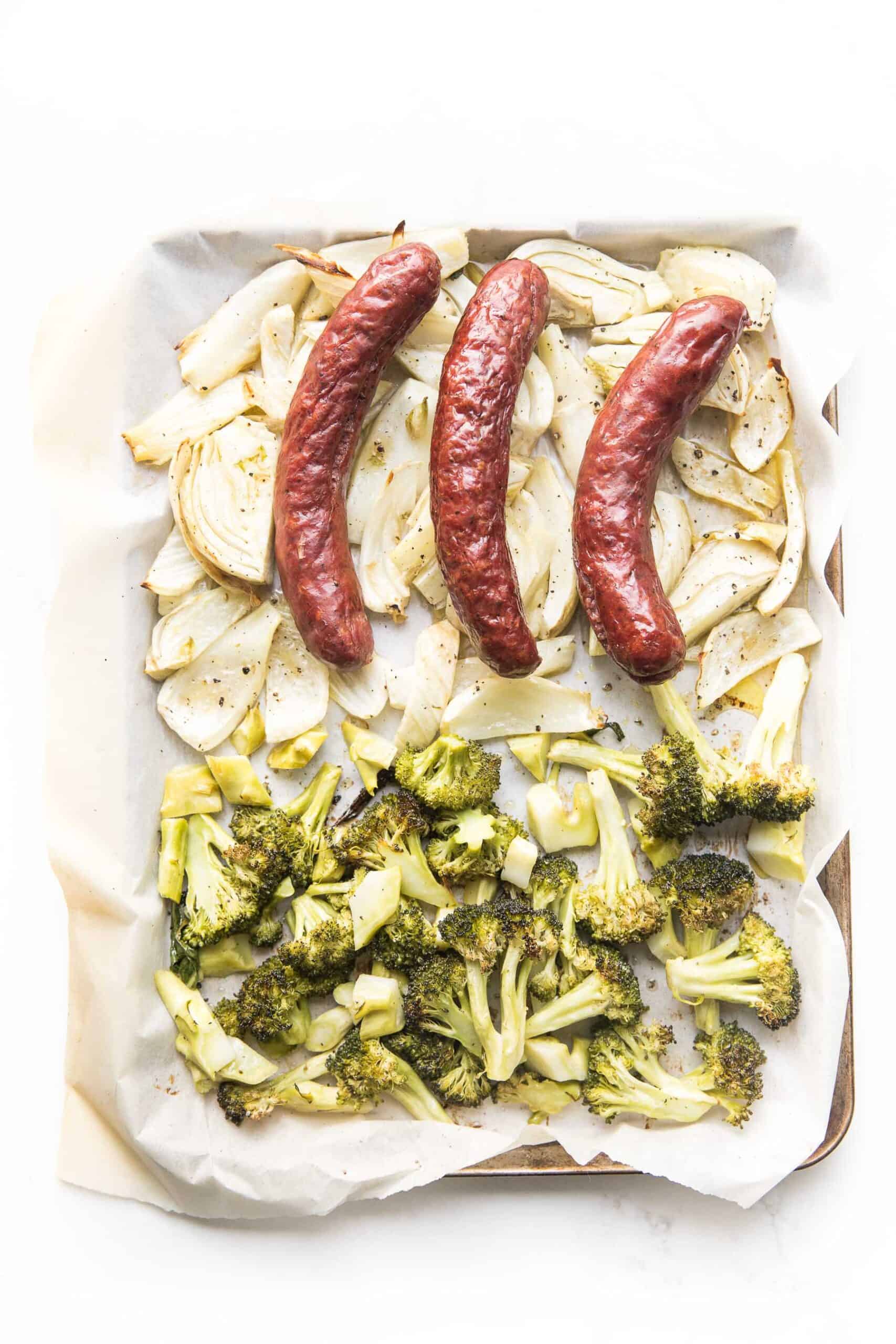 sausage, roasted fennel and broccoli on a sheet pan and white background