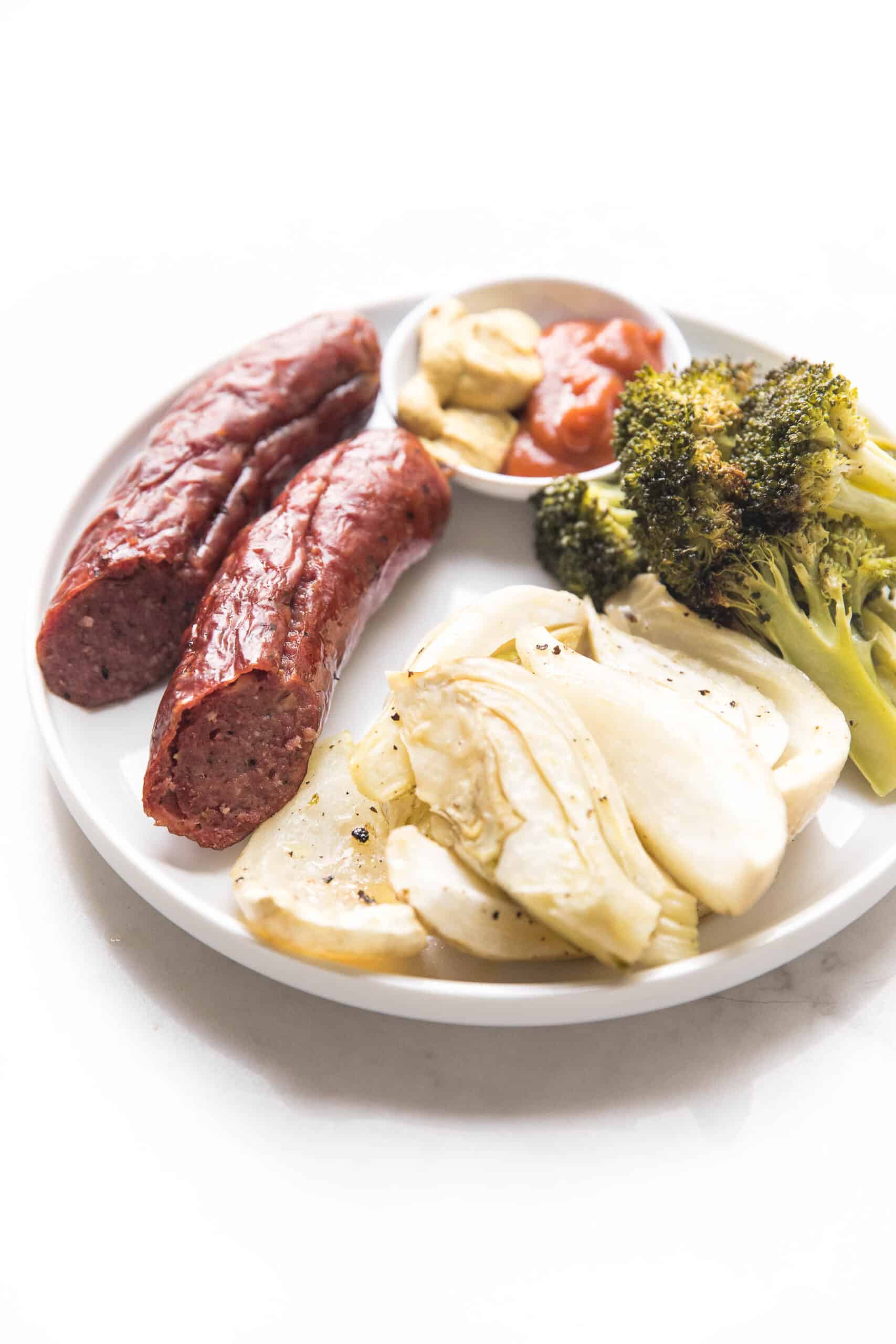 sausage, roasted fennel and broccoli on a white plate and background
