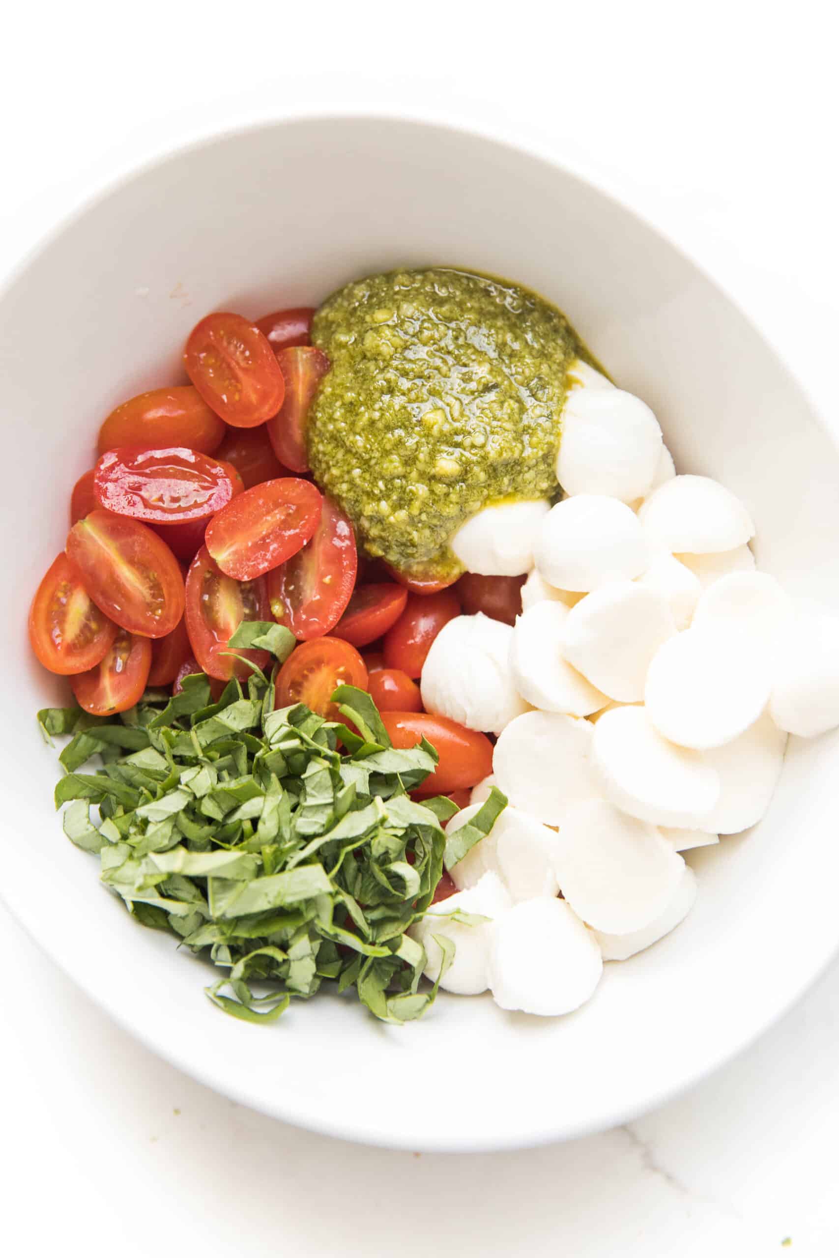 pesto caprese salad in a white bowl