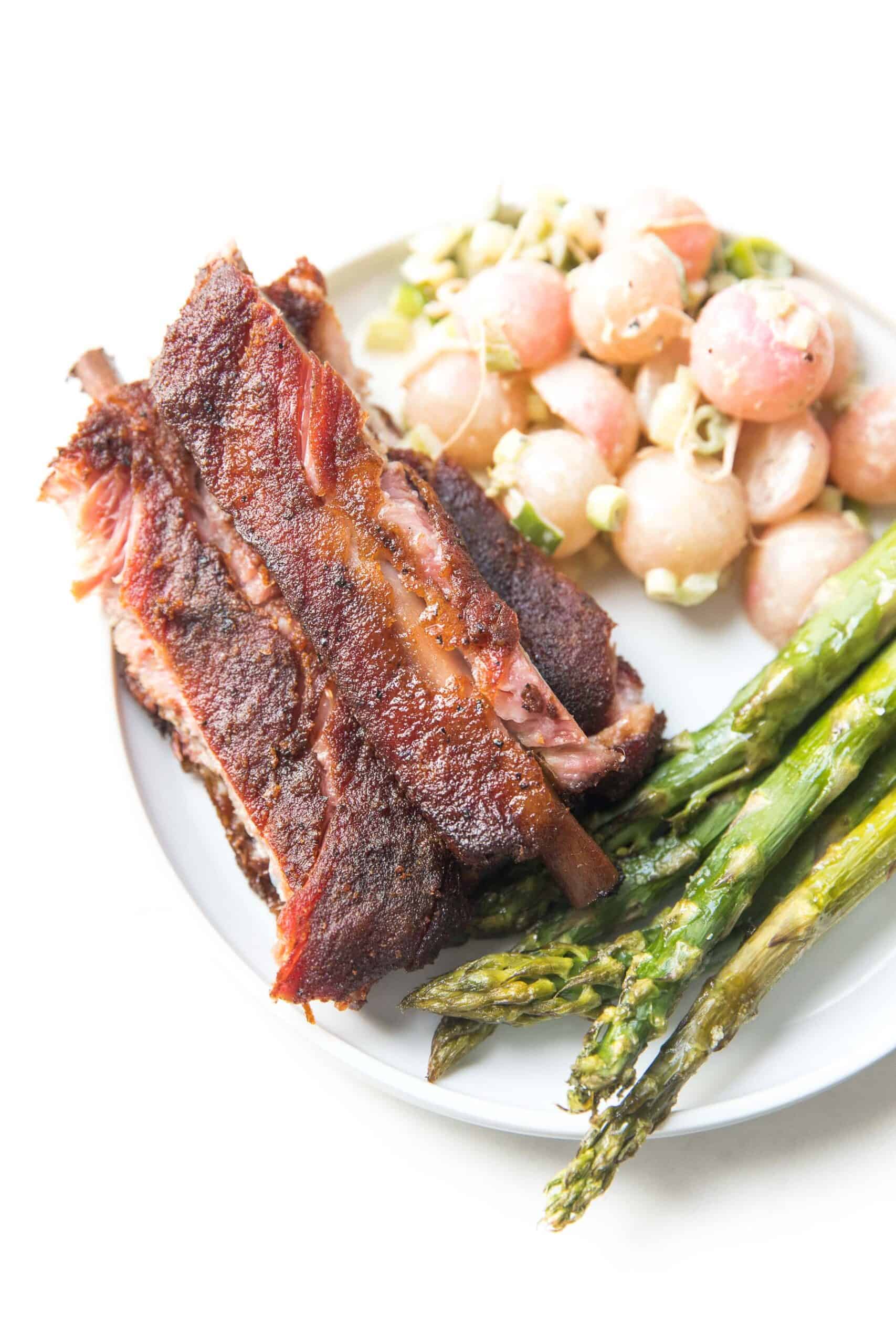 plate of ribs on a white background with asparagus and keto potato salad