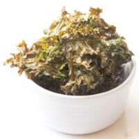 crispy kale chips in a white bowl in a white background