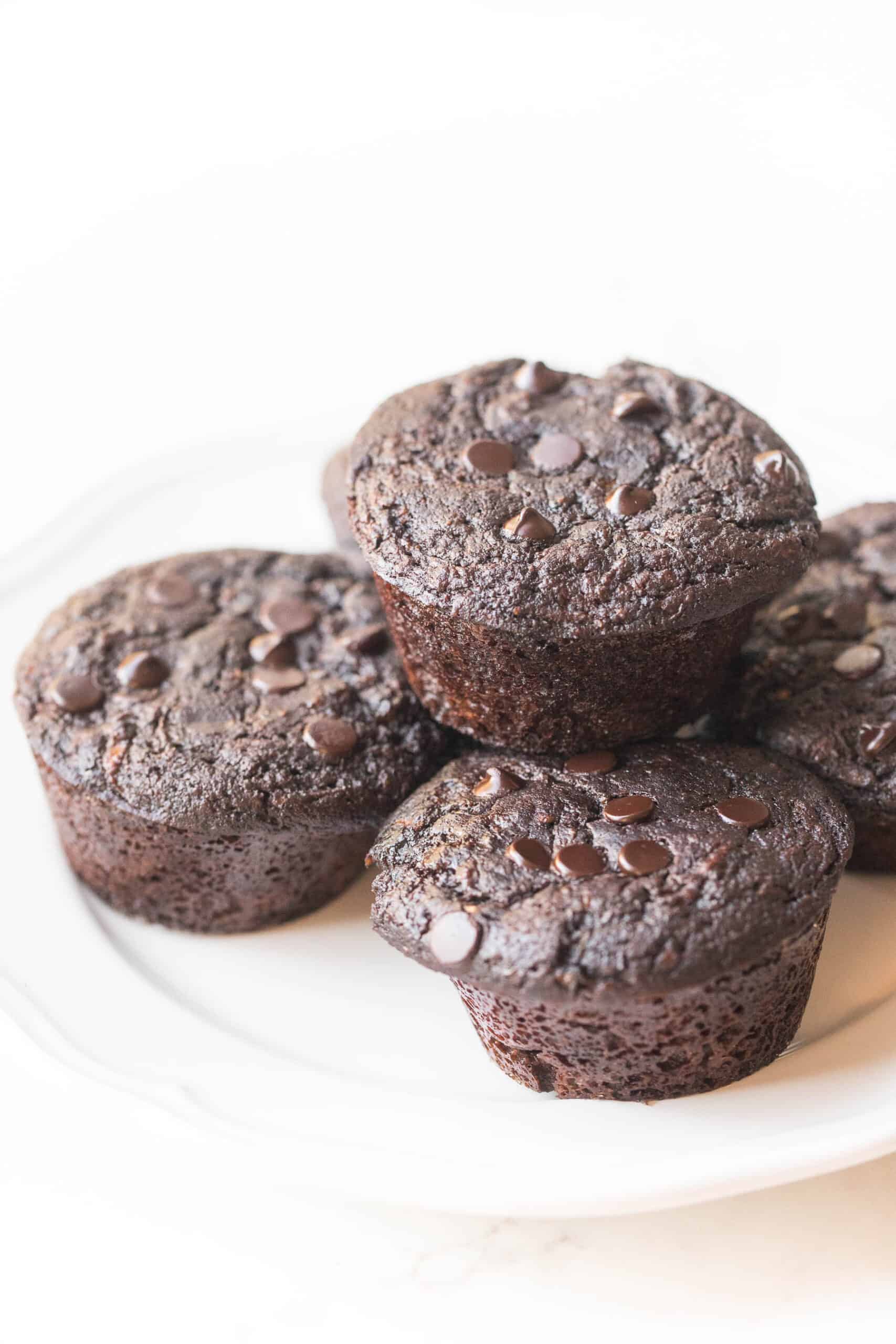 keto chocolate zucchini muffins on a white plate and background