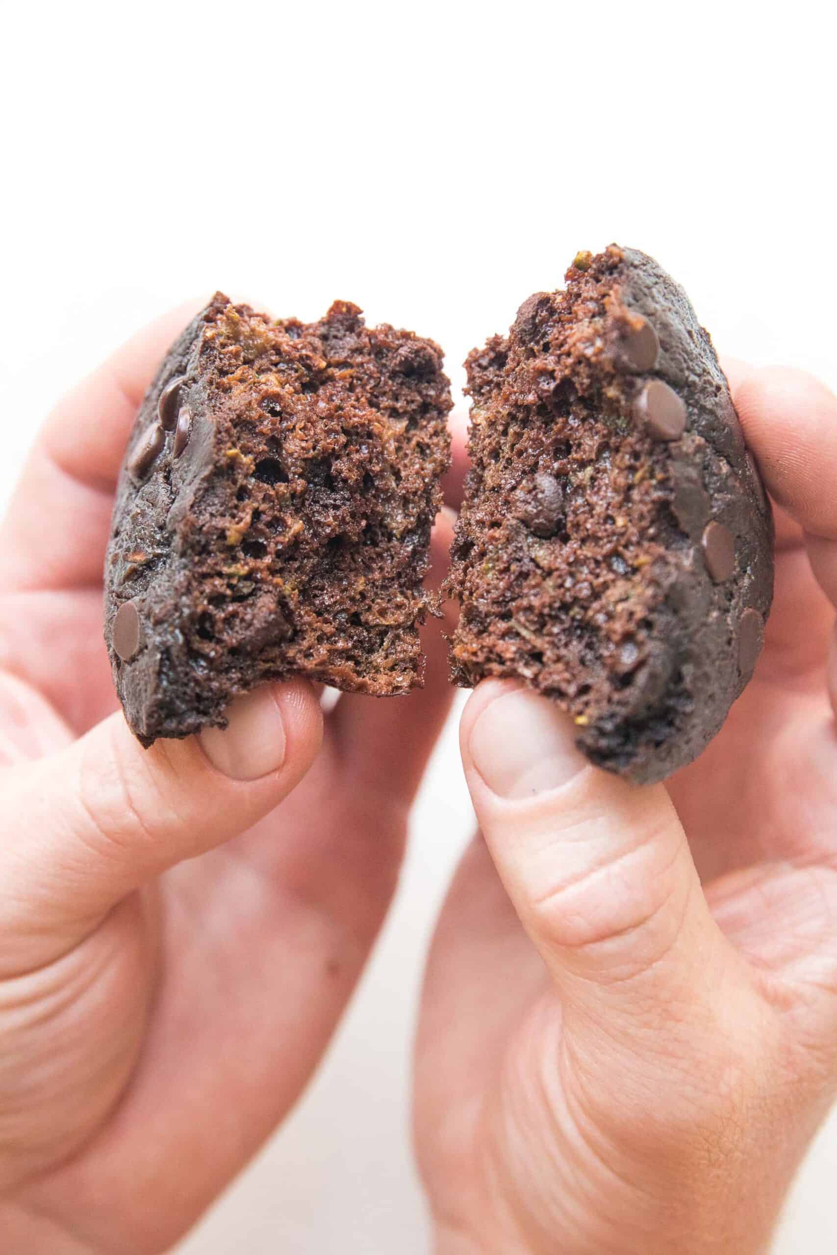 hand breaking open keto chocolate zucchini muffins