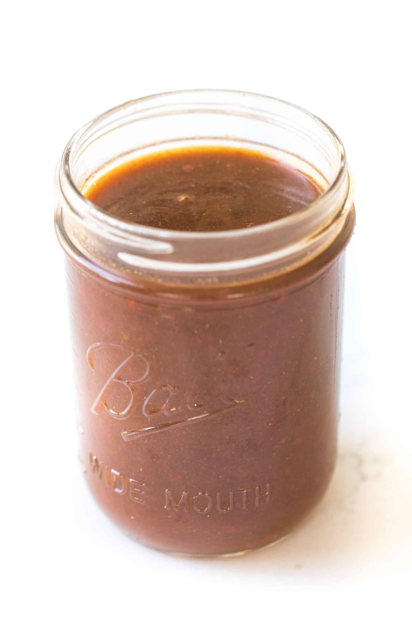 mason jar of homemade red enchilada sauce on a white background