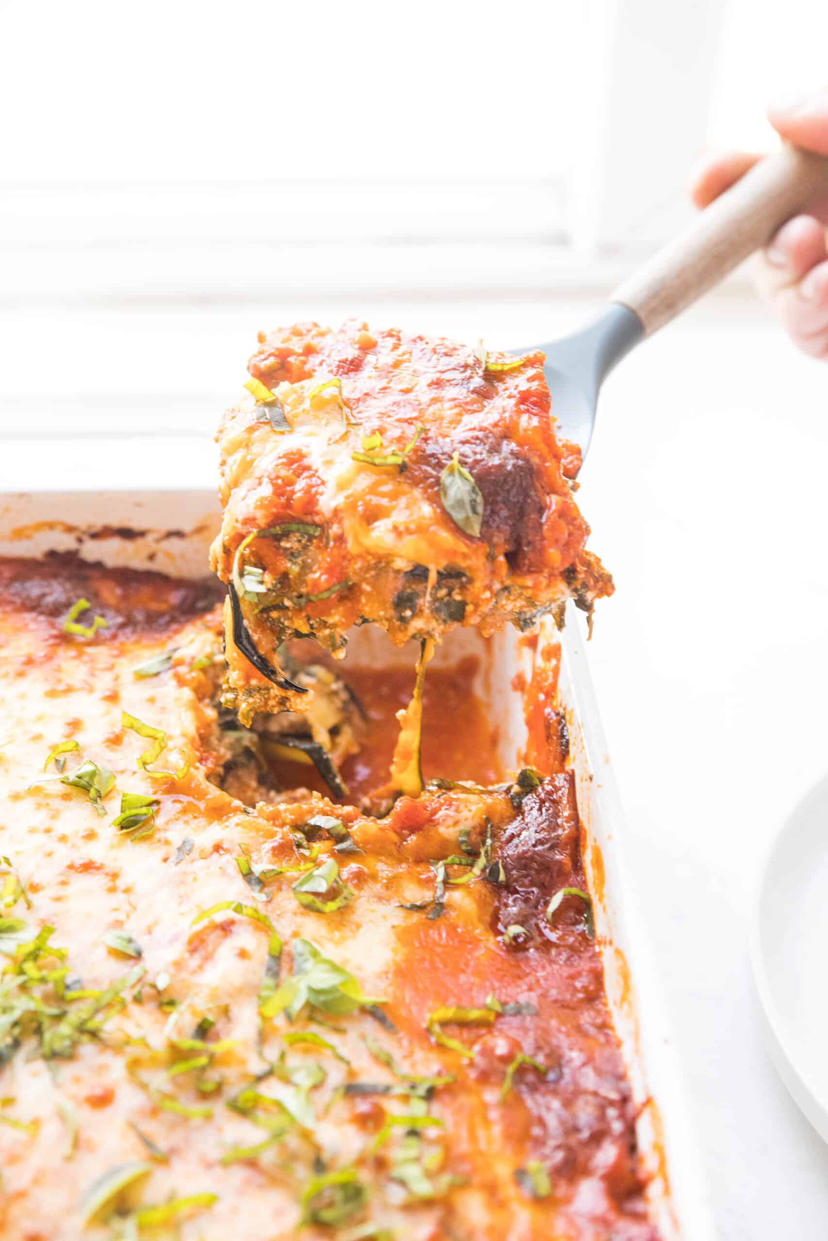 spooning out a portion of keto low carb lasagna made with zucchini noodles from the baking dish