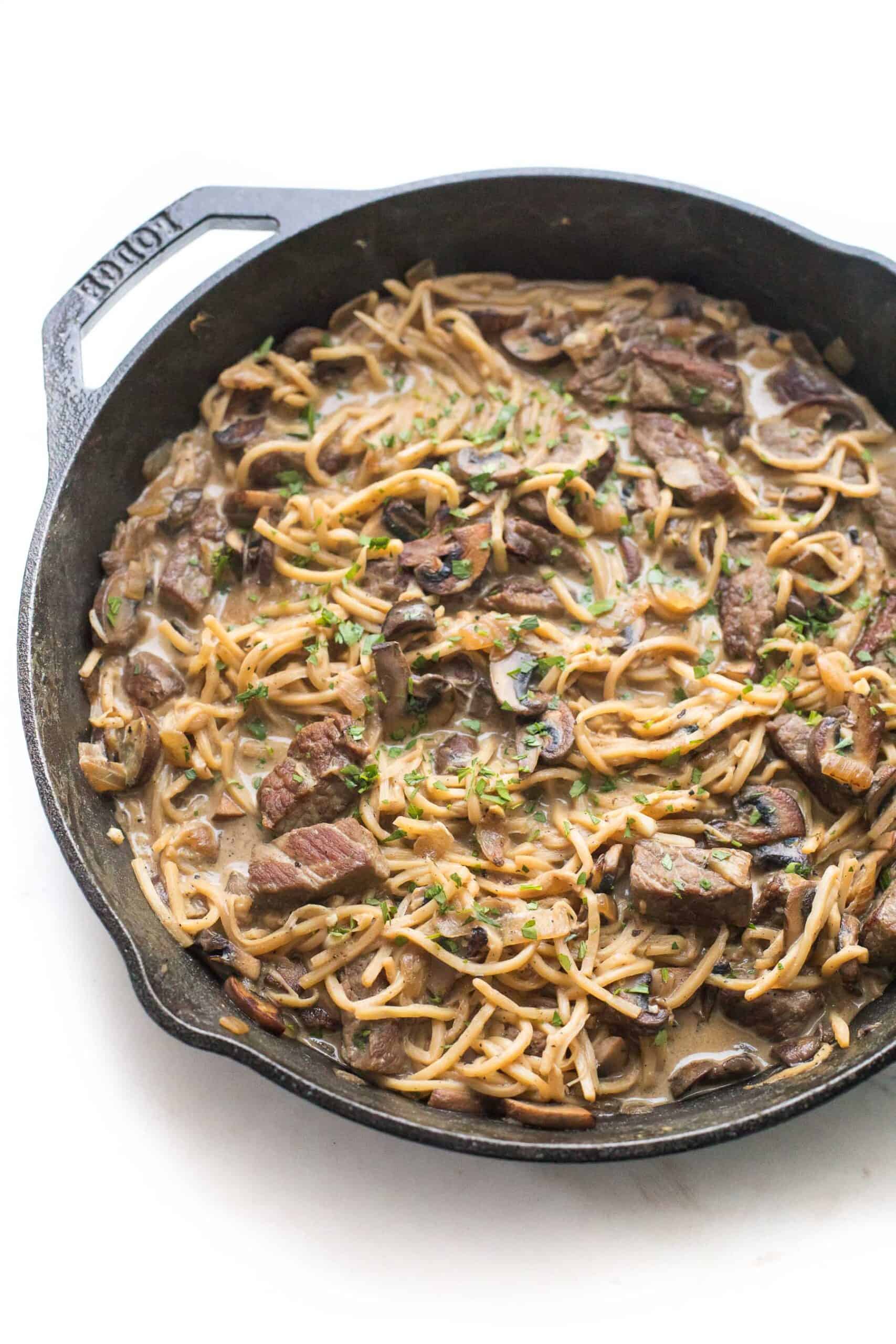 keto beef stroganoff in a cast iron skillet on a white background