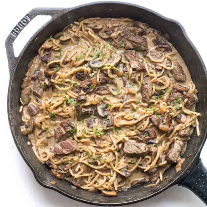 keto beef stroganoff in a cast iron skillet on a white background