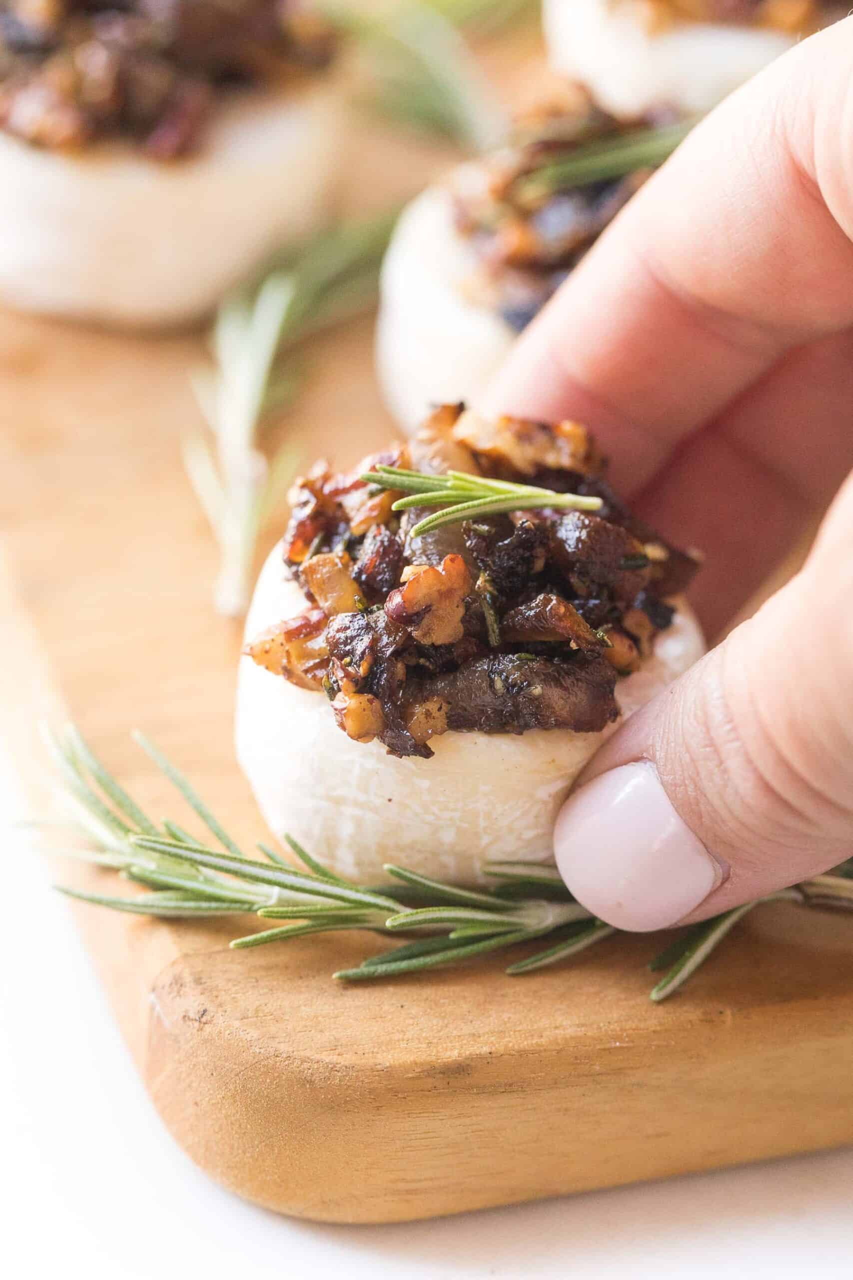 Brie cheese bites topped with caramelized onions, rosemary and pecan mixture on a cheese board