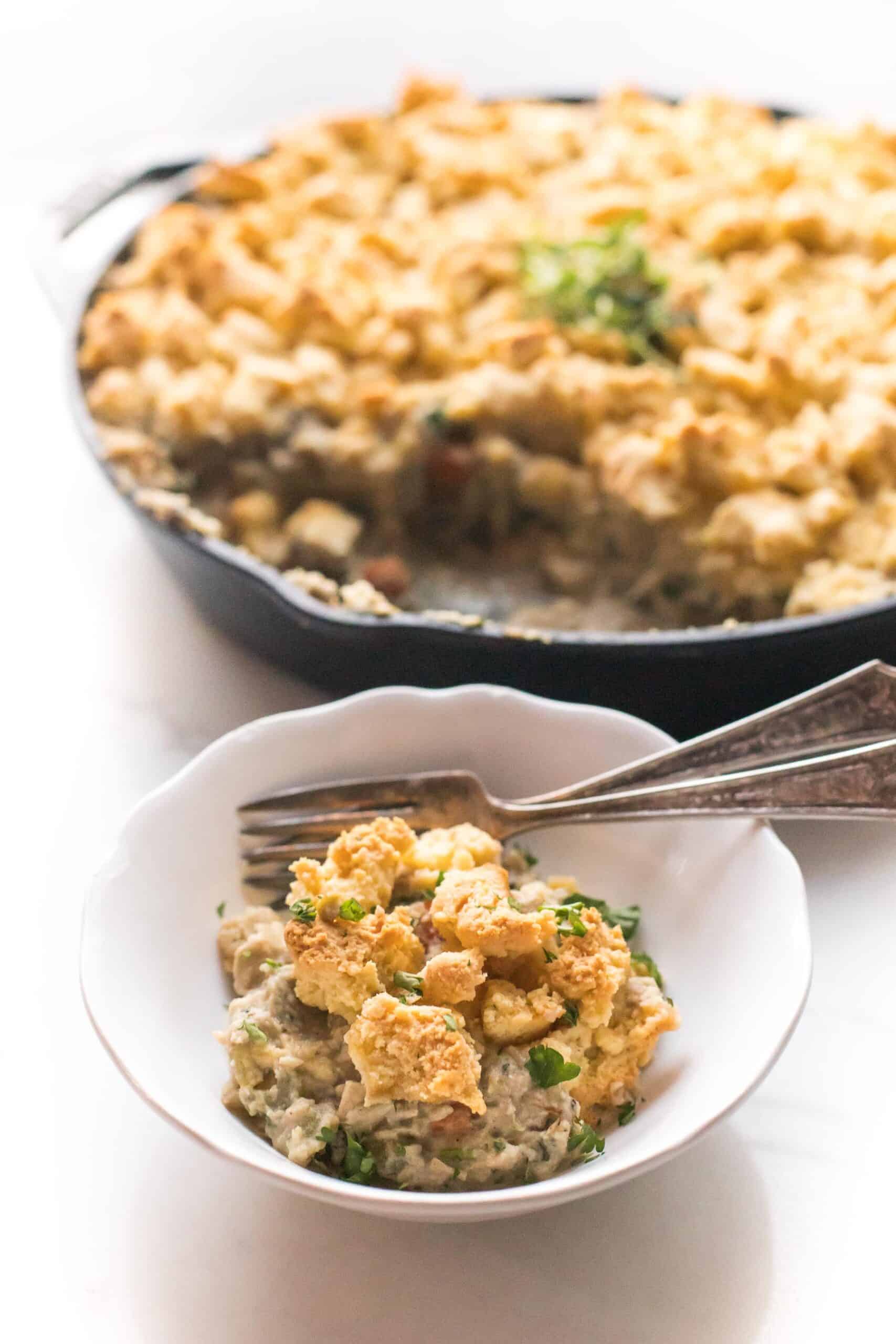 keto chicken pot pie crumble in a cast iron skillet and white bowl on a white background