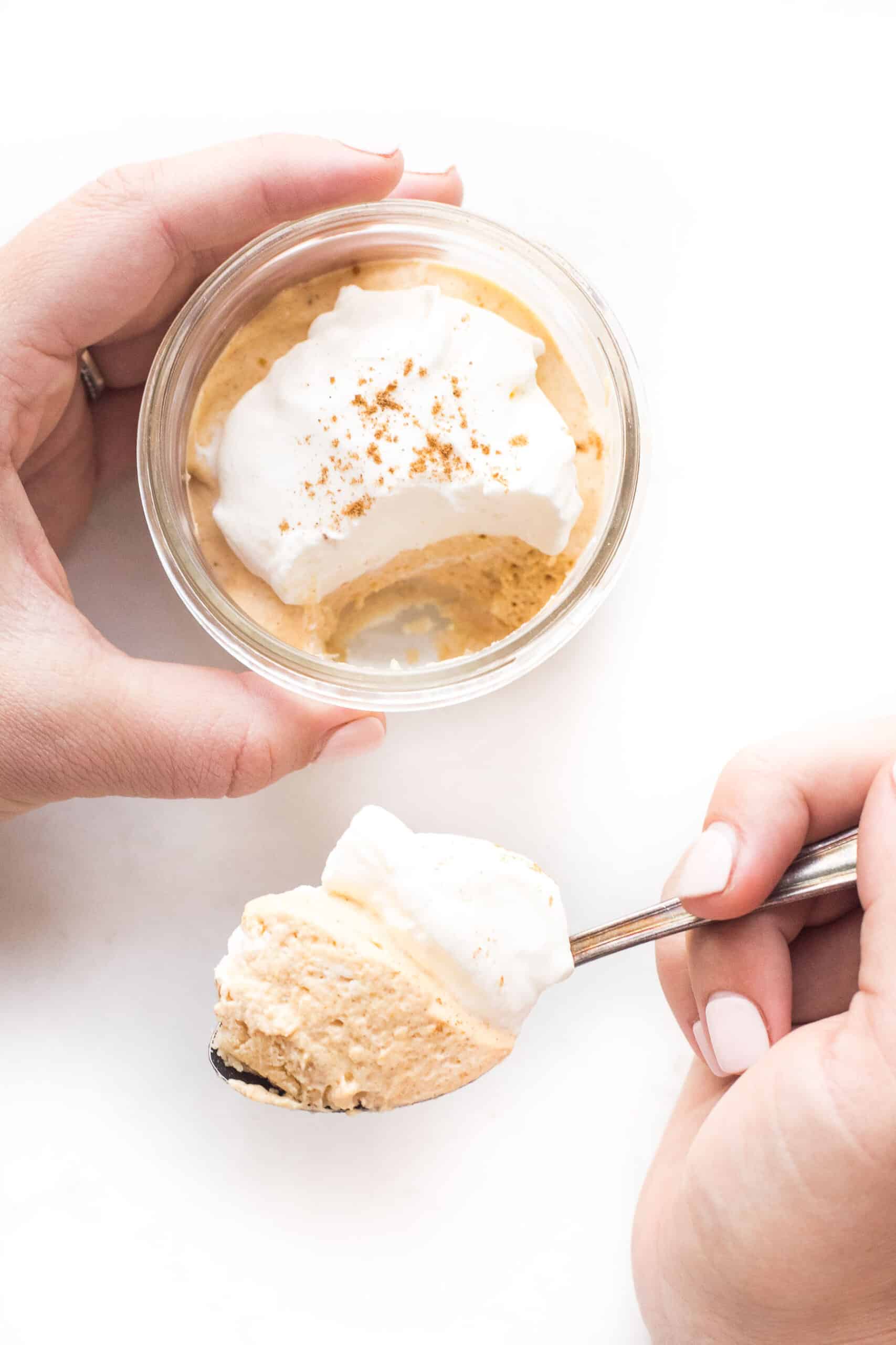 keto pumpkin cheesecake in a mason jar, hand spooning out a bite