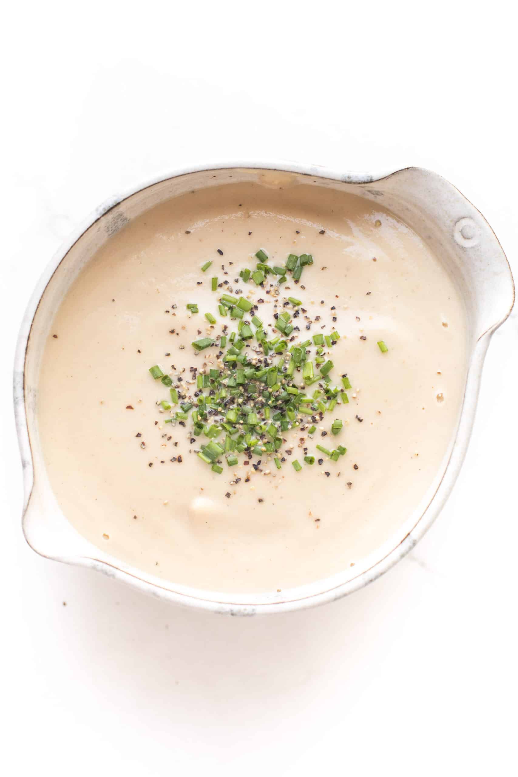 keto roasted cauliflower soup in a pottery bowl topped with chives and black pepper