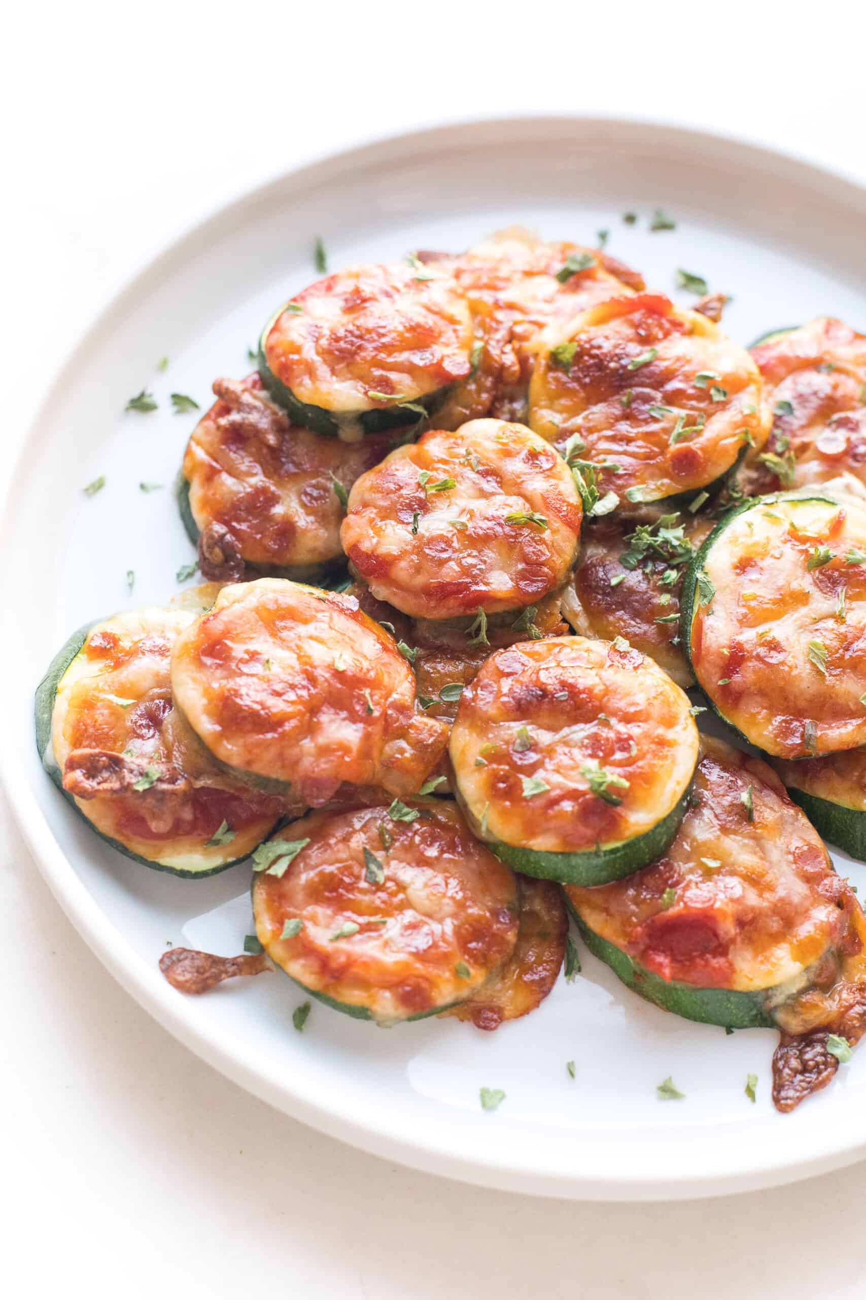 keto mini zucchini pizza bites on a white plate and background