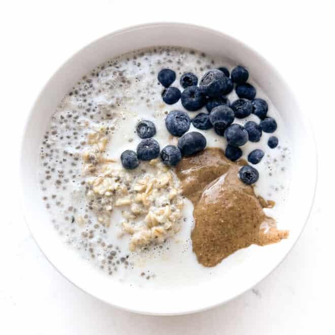 Oatmeal in a white bowl with nut butter and blueberries