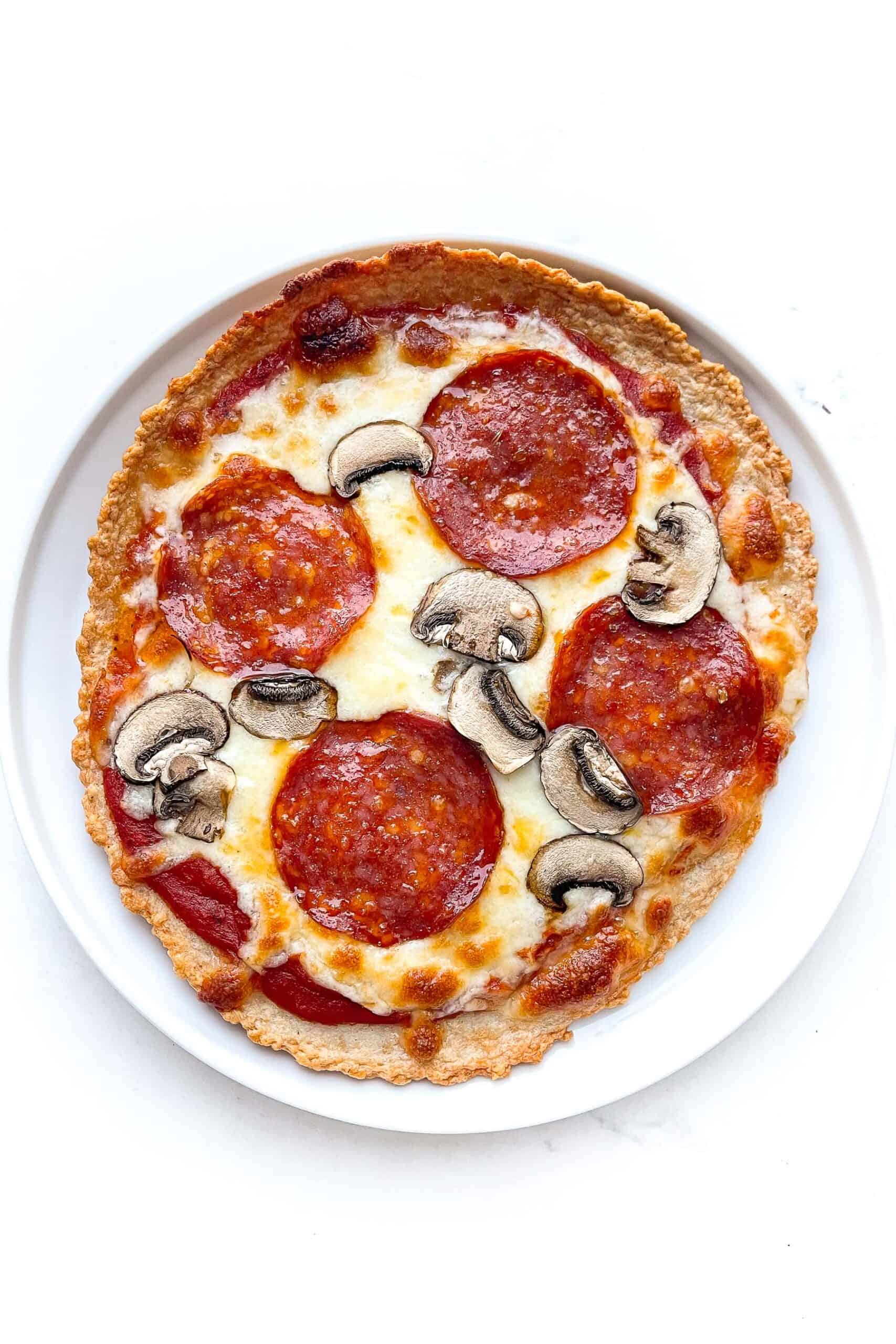 zero carb pepperoni and mushroom pizza on a white plate and background