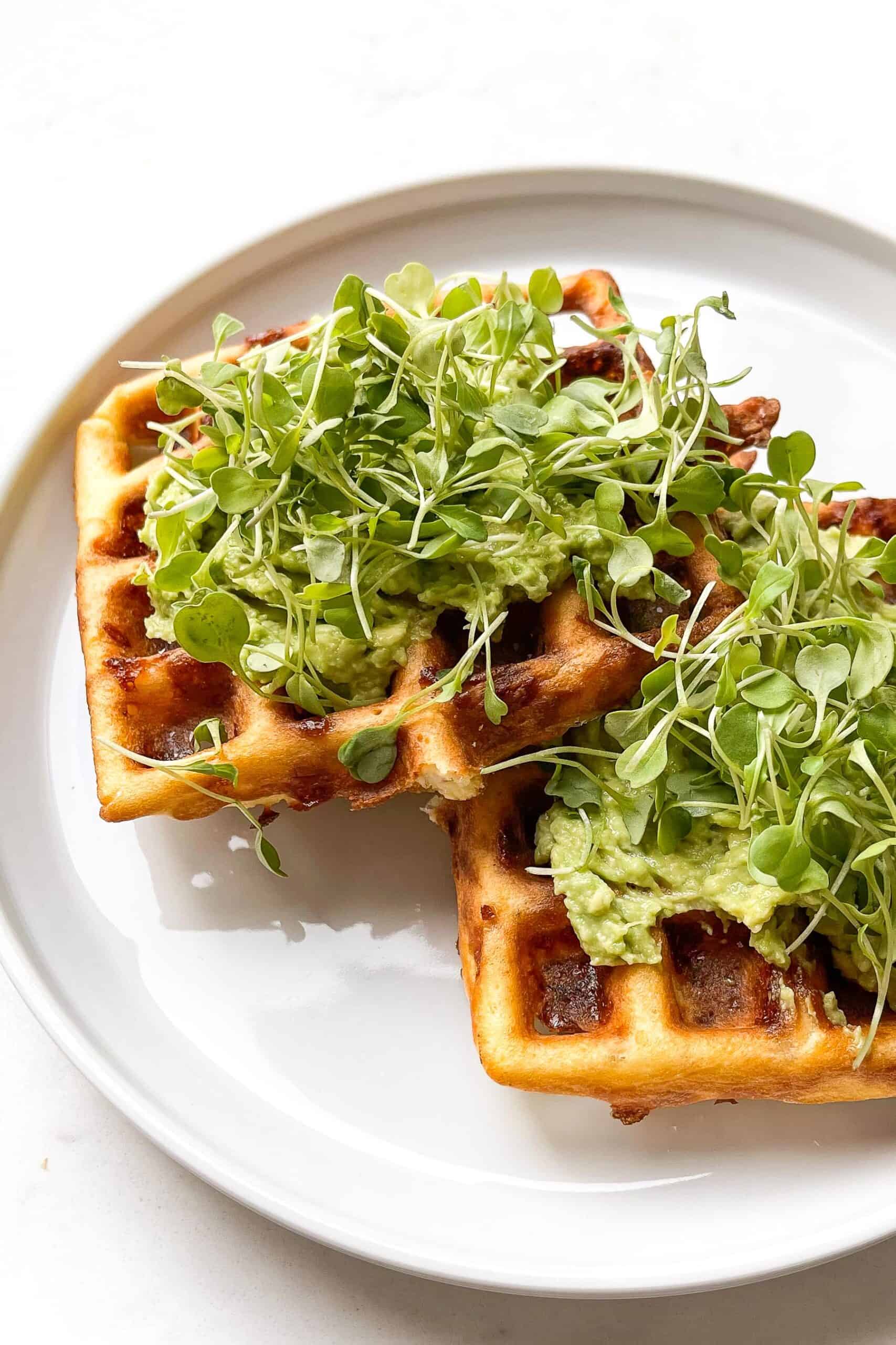 two keto chaffles topped with avocado and microgreens