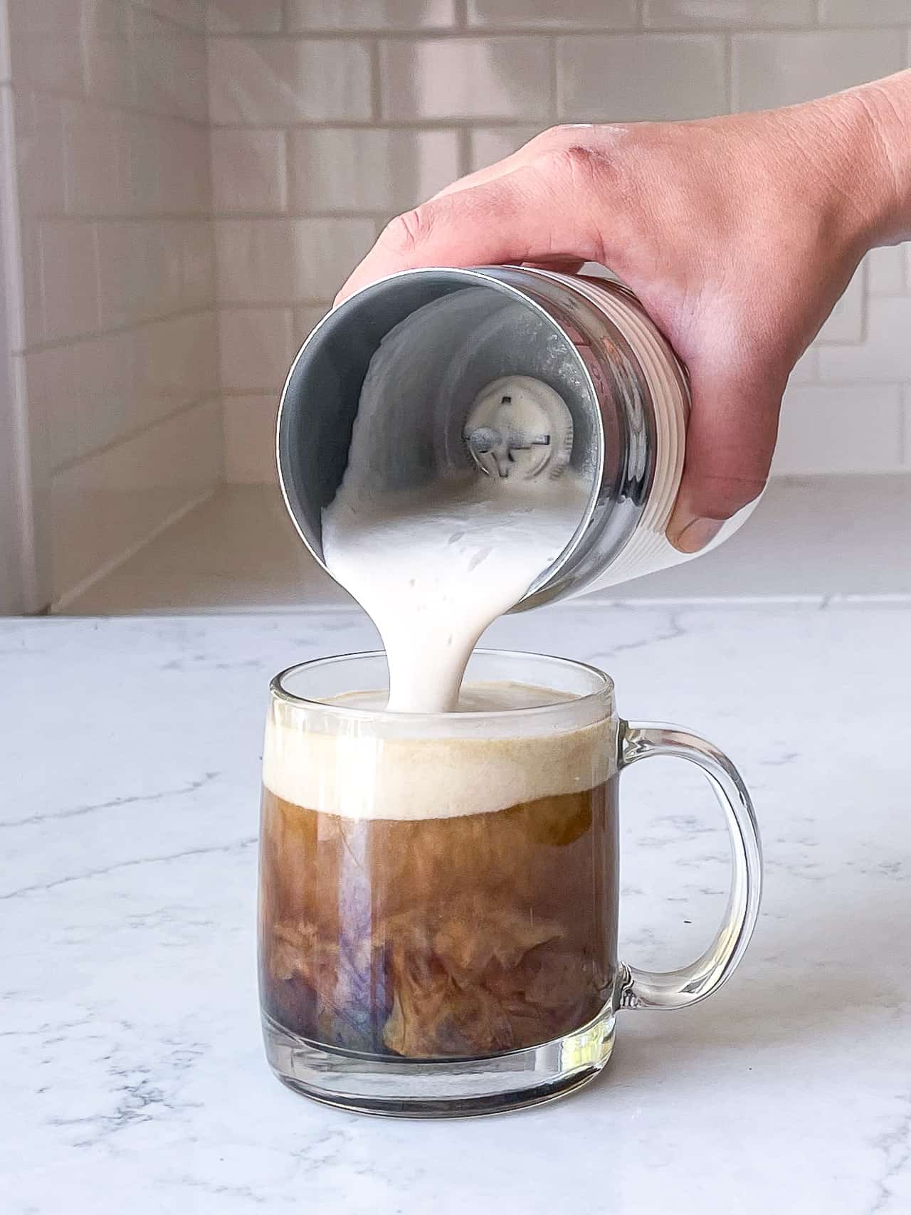 pouring frothed milk into coffee