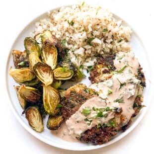 keto southwest tuna cakes topped with sauce on a white plate and background with roasted brussels sprouts and cauliflower rice