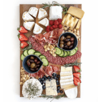 Keto friendly cheese board with sliced cheese, salami, cucumber, nuts, olives and berries