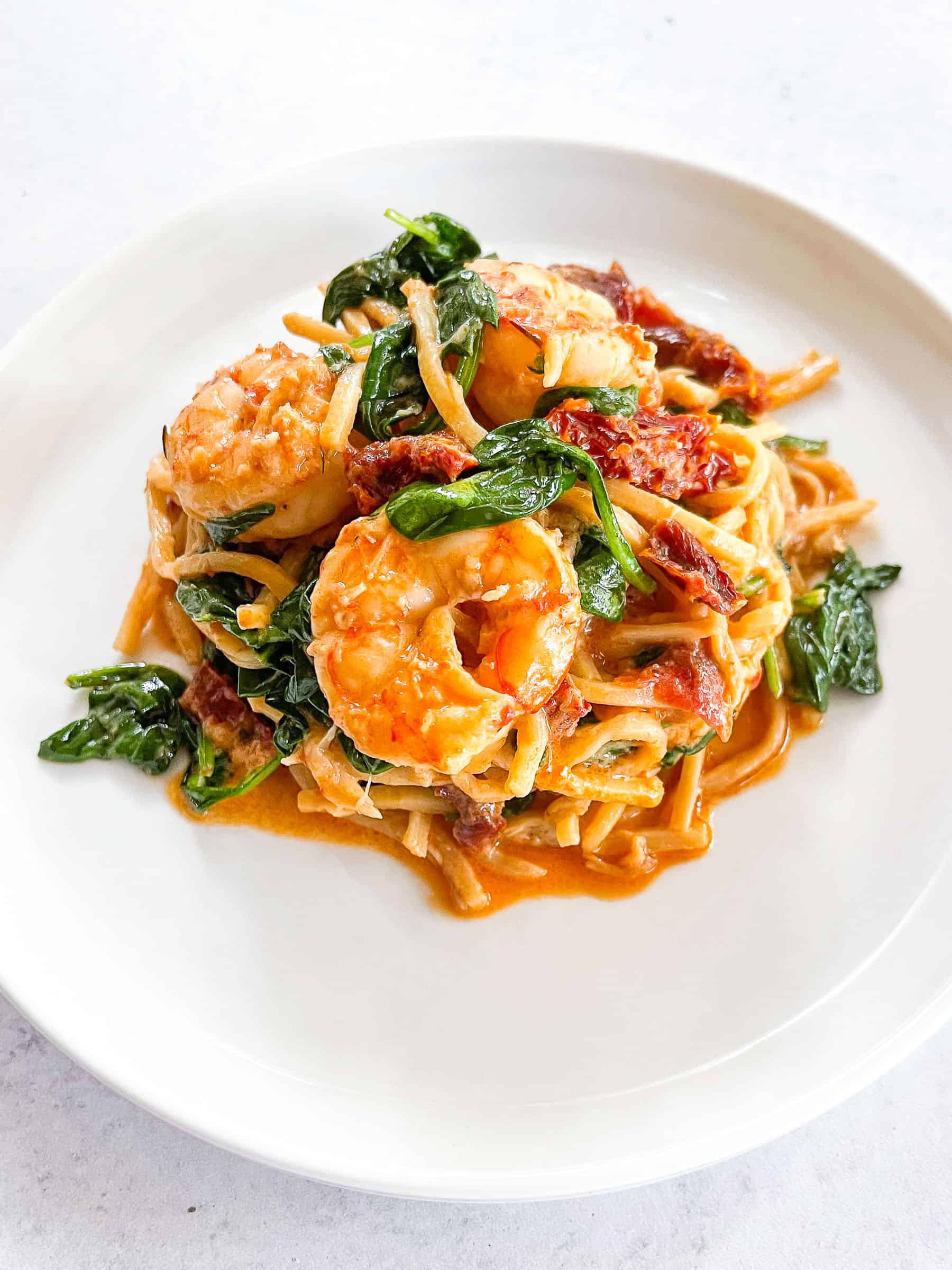 keto creamy tuscan shrimp pasta on a white plate with a white background