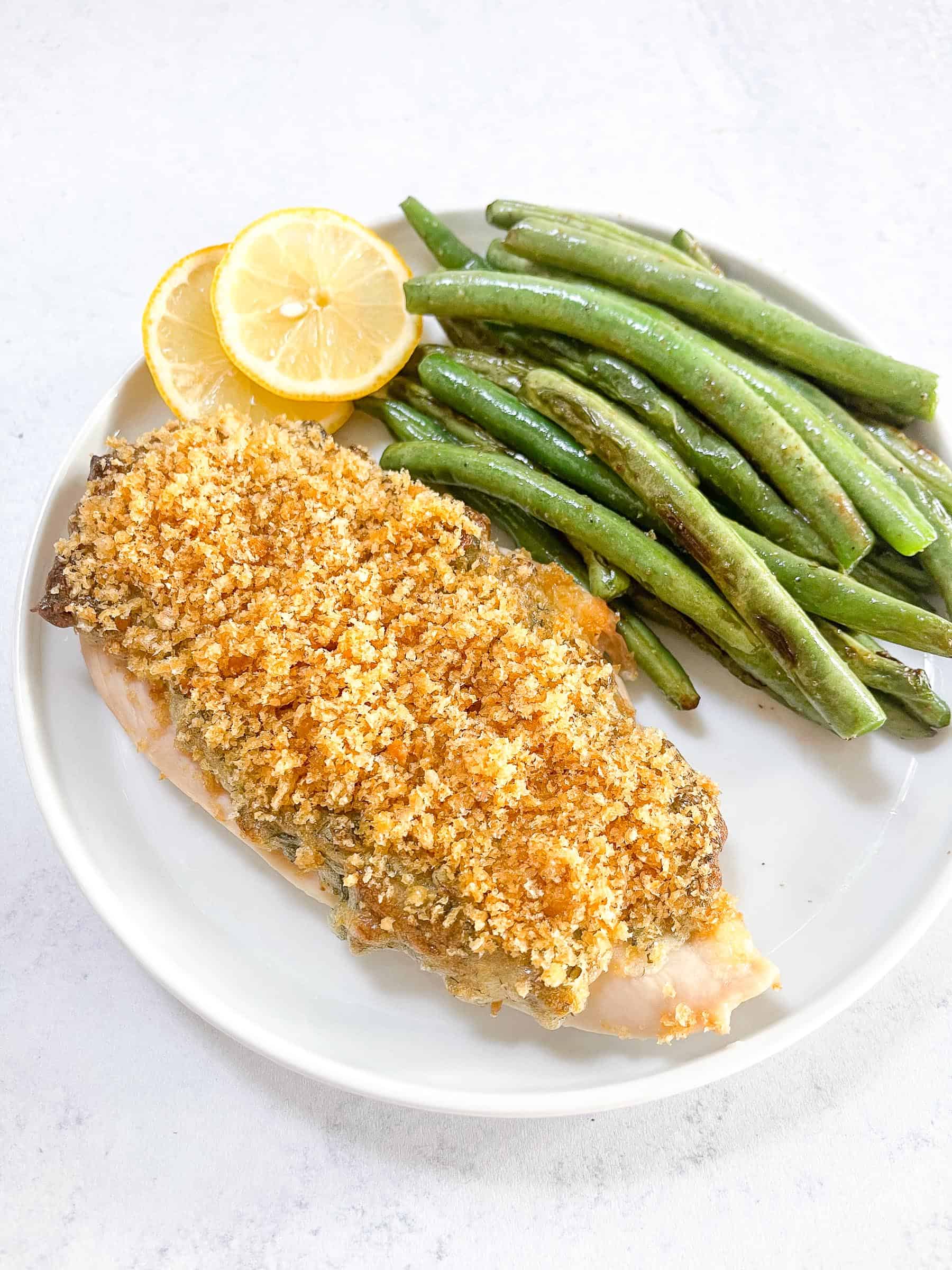 keto crispy ranch chicken with green beans and lemon garnish on a white plate with a white background