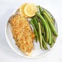 keto crispy ranch chicken with green beans and lemon garnish on a white plate with a white background