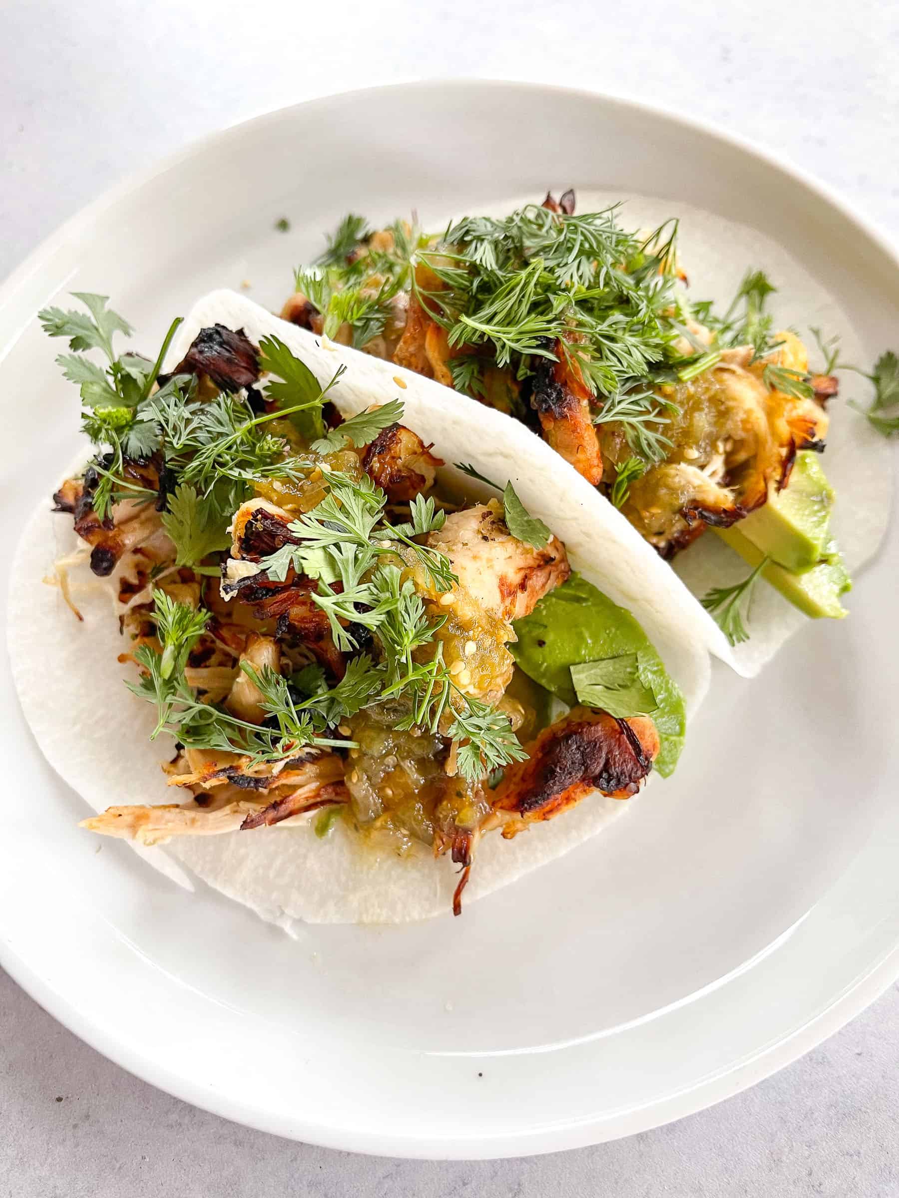 keto crispy verde chicken tacos on jicama wrap with cilantro on a white plate with a white background