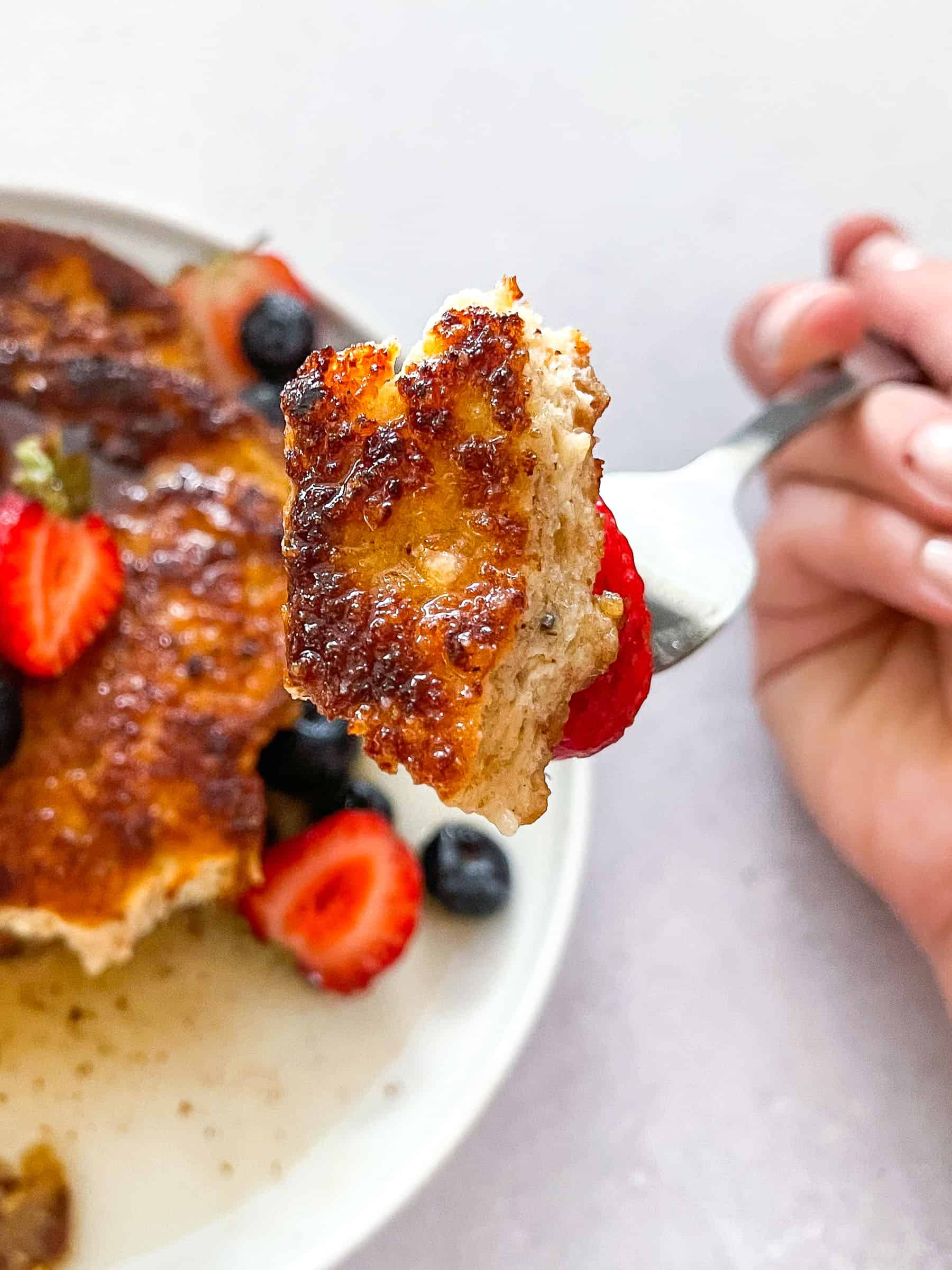 keto crusted french toast topped with syrup, blueberries, and strawberries on a white plate with a white background