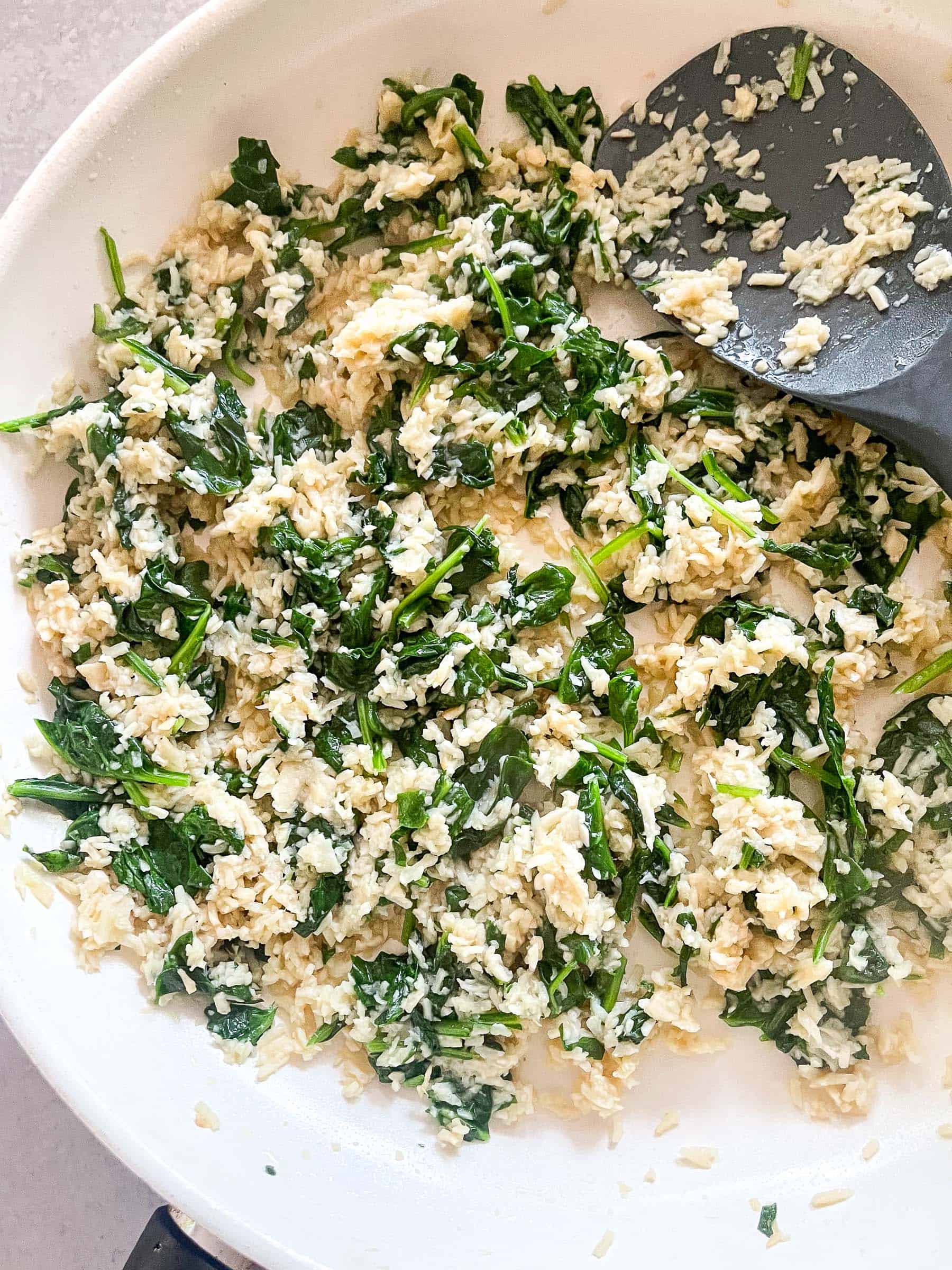 spinach and hearts of palm rice in a white bowl with a silver spoon