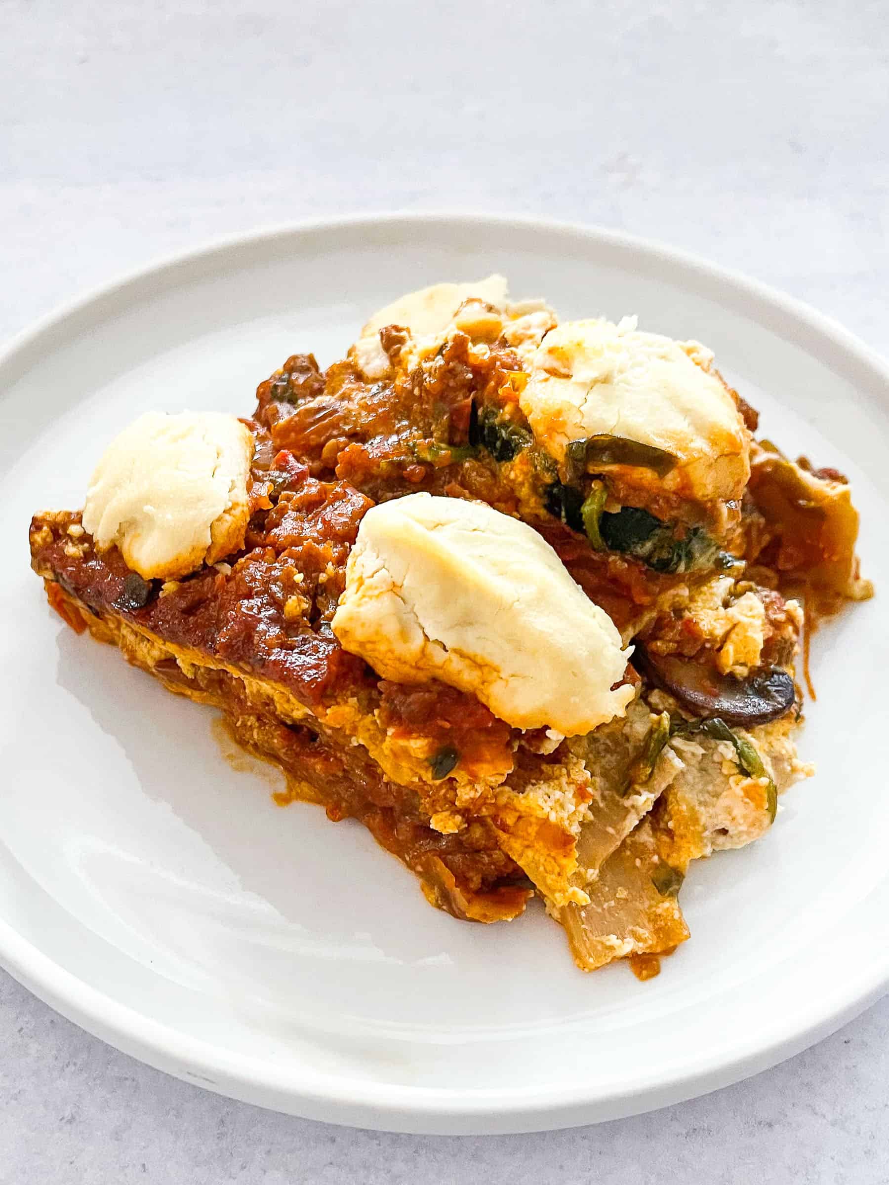 dairy free lasagna topped with dairy free ricotta cheese on a white plate with a white background