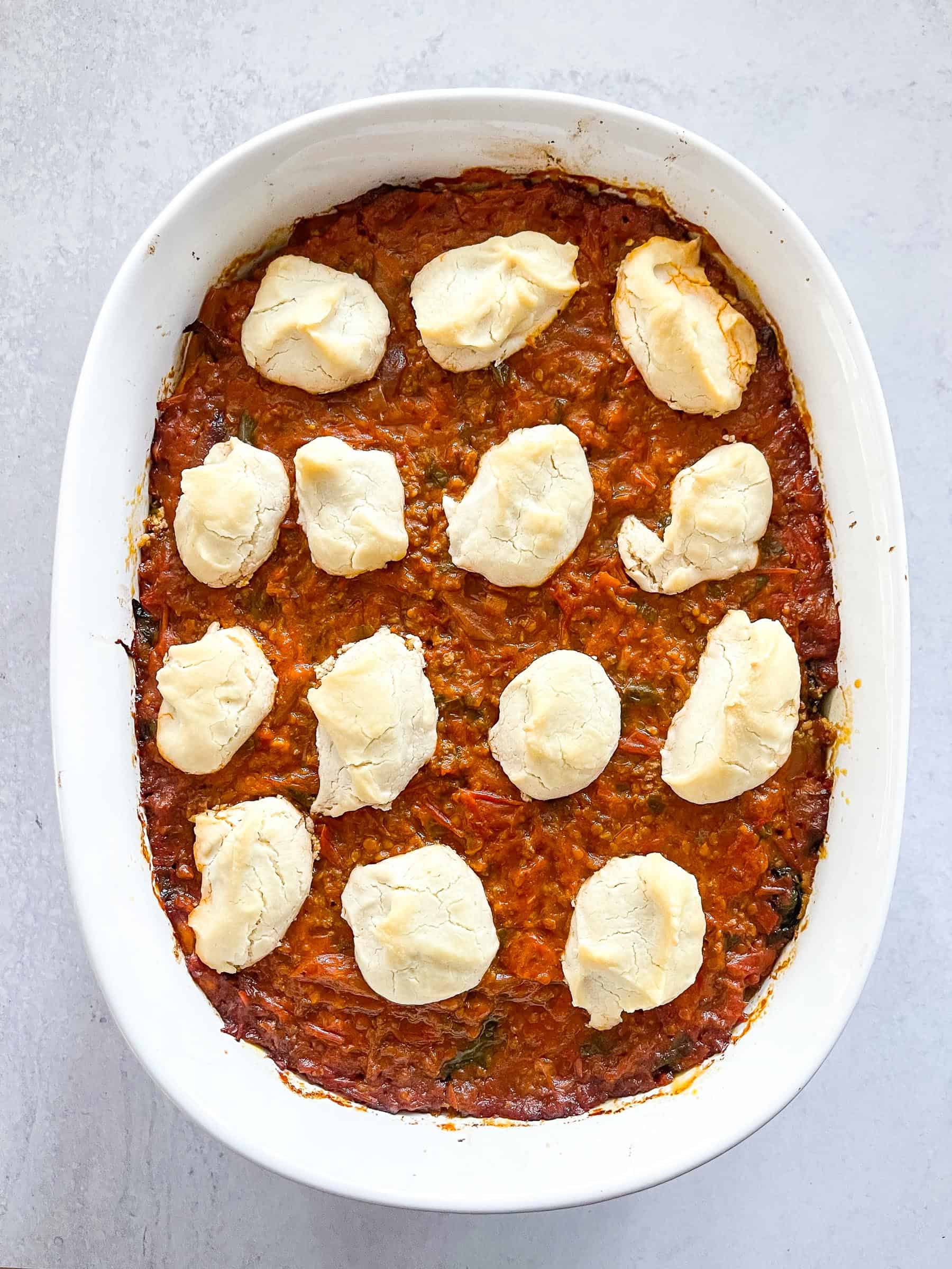 dairy free lasagna topped with dairy free ricotta cheese in a white baking dish with a white background