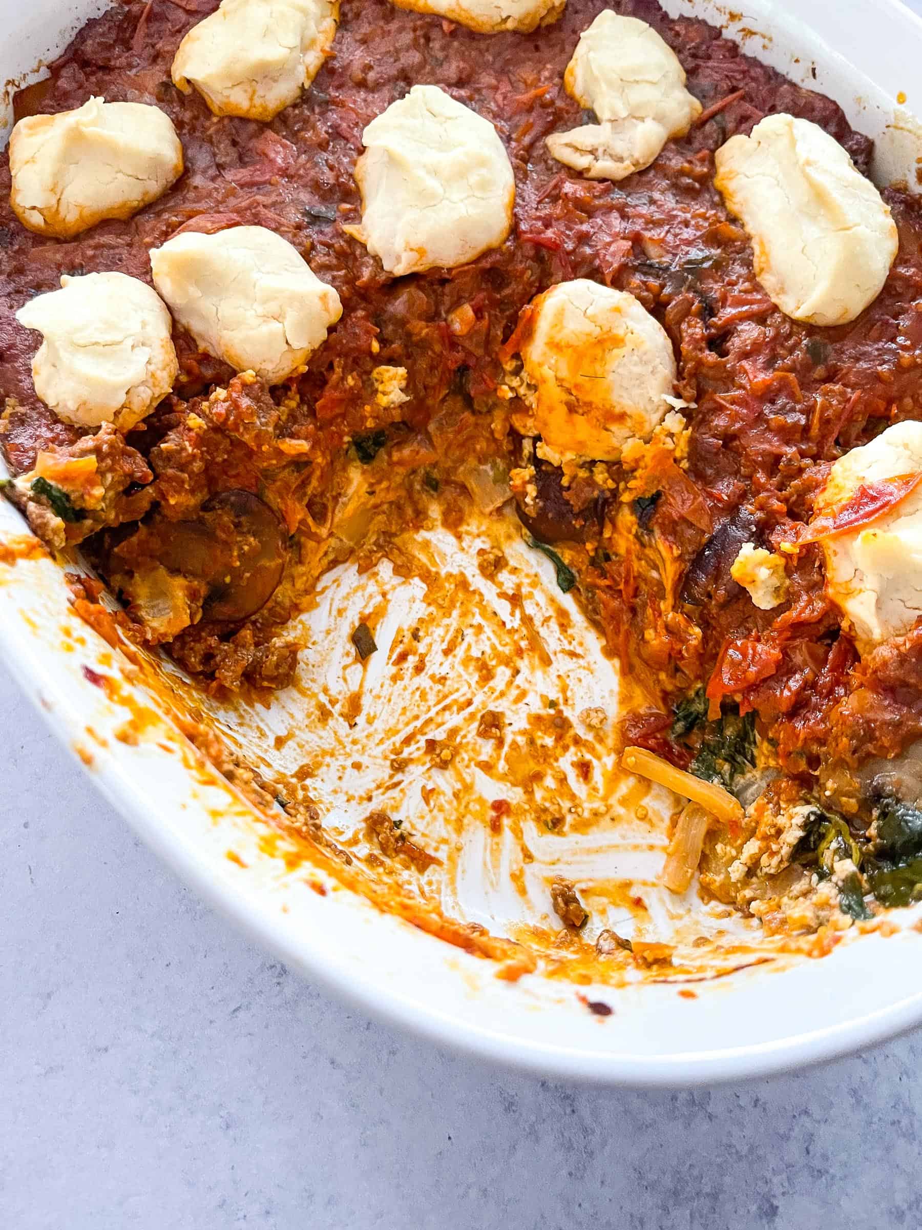 dairy free lasagna topped with dairy free ricotta cheese on a white plate with a white background