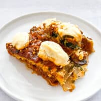 dairy free lasagna topped with dairy free ricotta cheese on a white plate with a white background