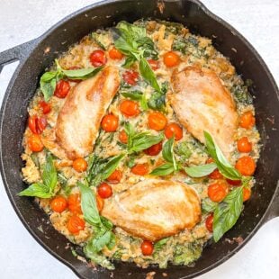 keto creamy chicken and tomato casserole in a black cast iron skillet with a white background