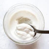 an overhead shot of a small jar of keto coconut yogurt with a silver spoon