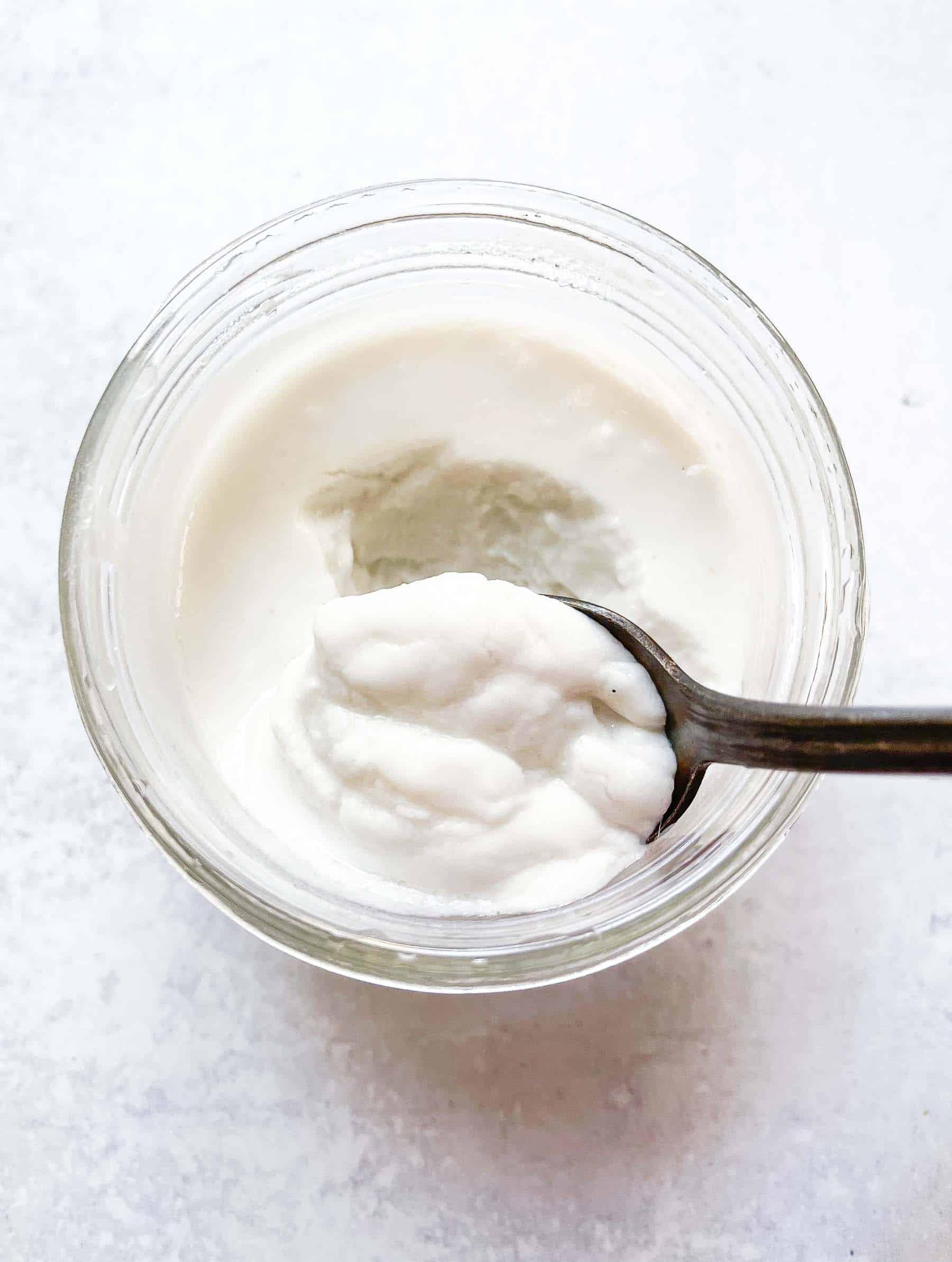 an overhead shot of a small jar of keto yogurt with a silver spoon resting inside