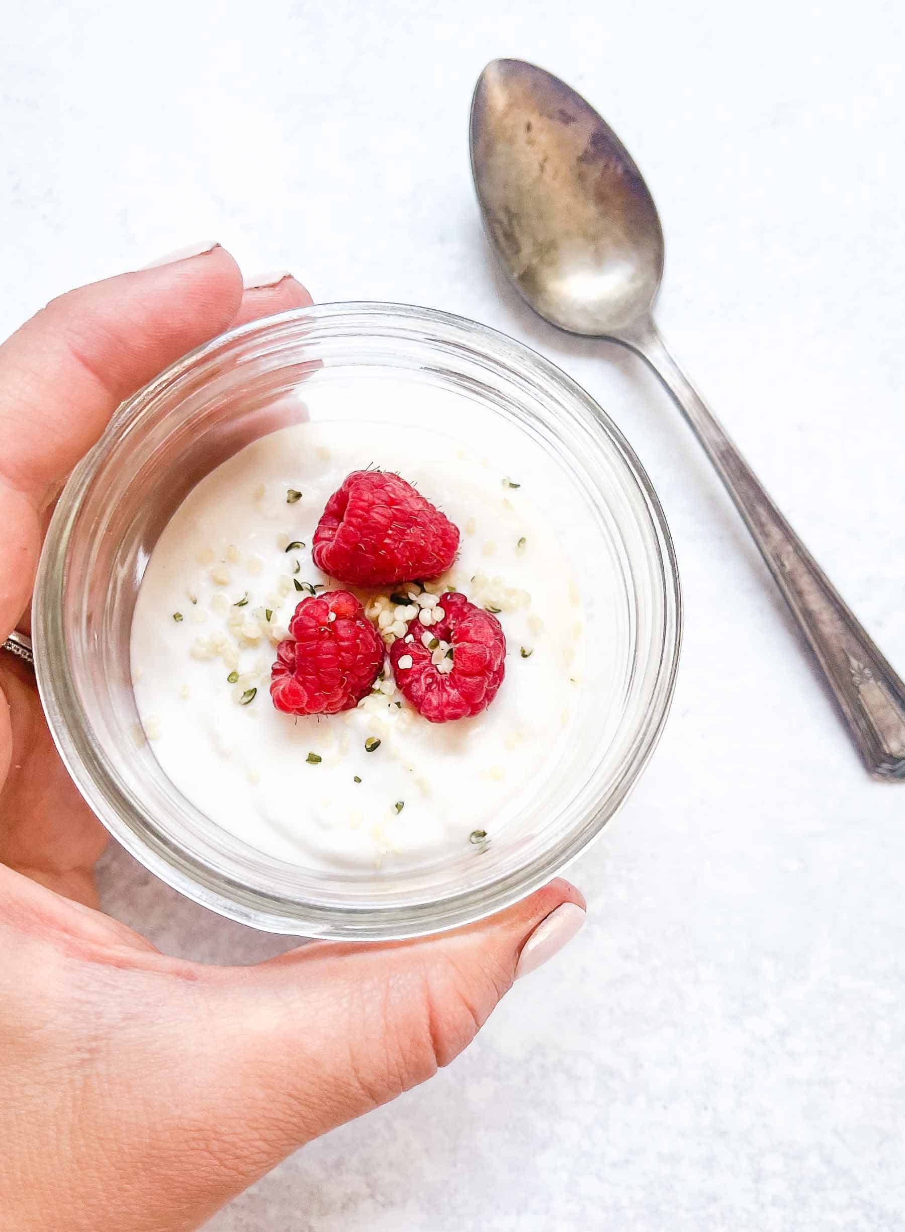 coconut milk yogurt in a small jar topped with berries and seeds