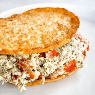 keto pesto chicken salad on cauliflower thins on a white plate with a white background