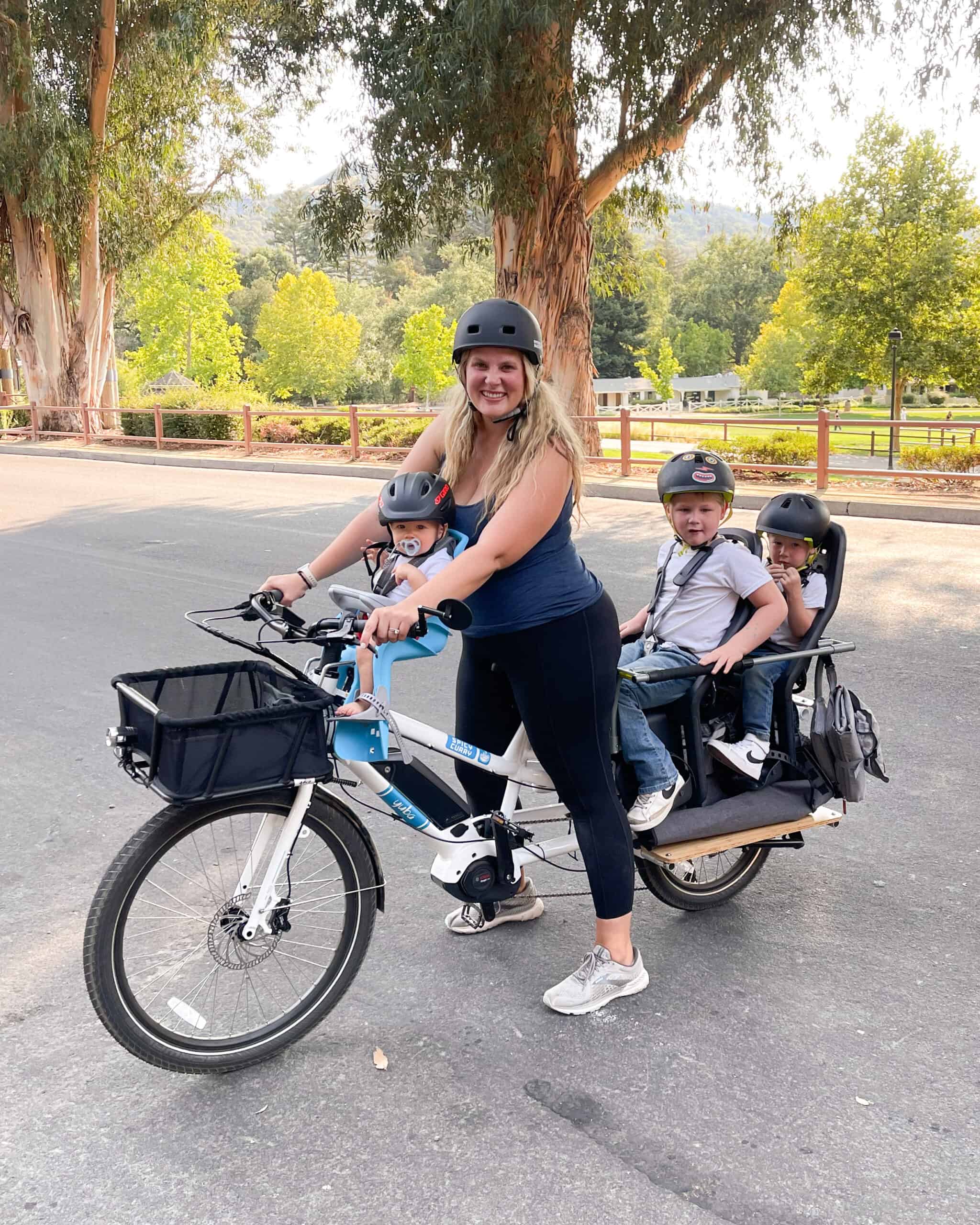 a mom riding on her family cargo bike with three kids