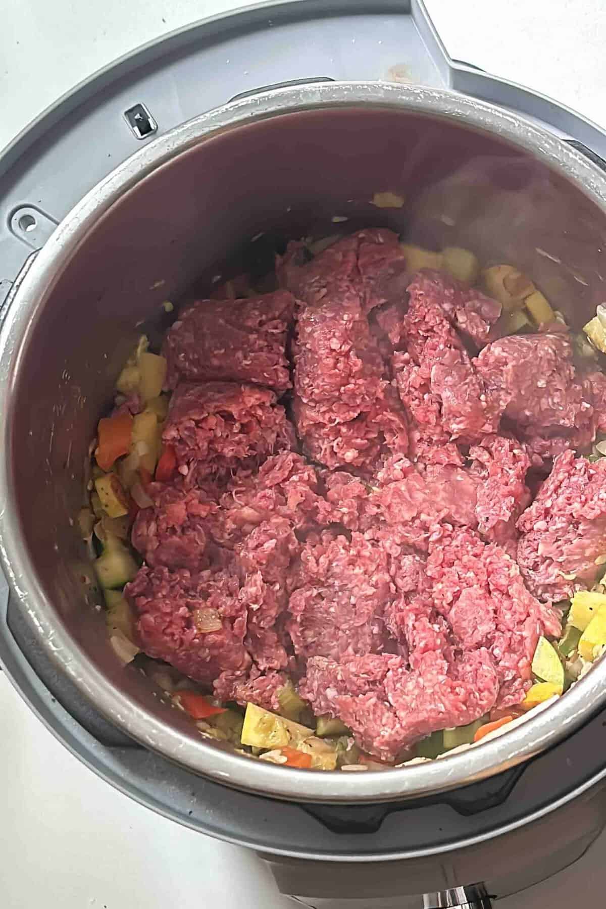 Ground beef cooking in an Instant Pot with vegetables