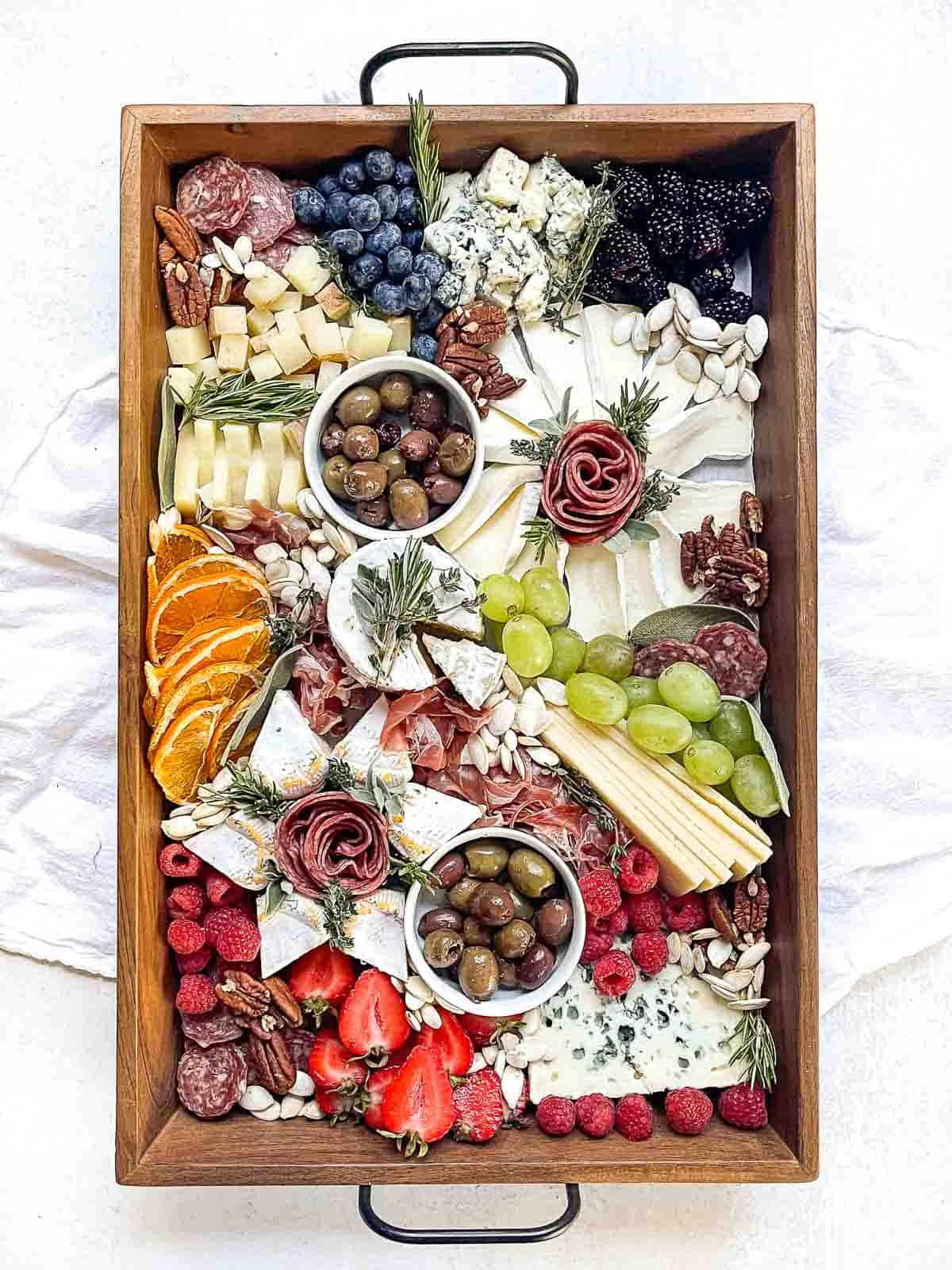 overhead shot of a styled christmas charcuterie board with cheeses, meats, fruit and nuts