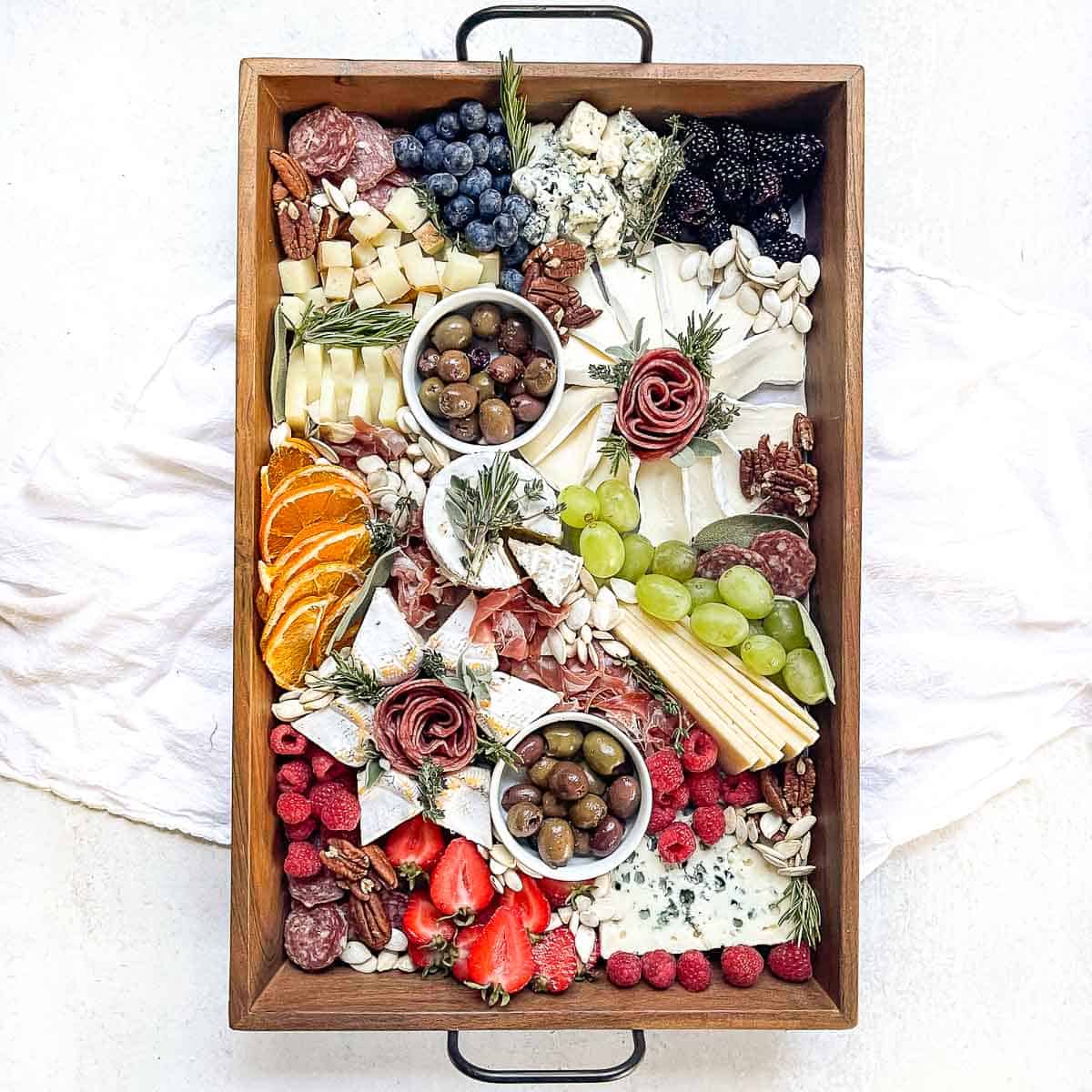 an overhead shot of a style cheese board filled with meats, cheese, fruits, and nuts. 